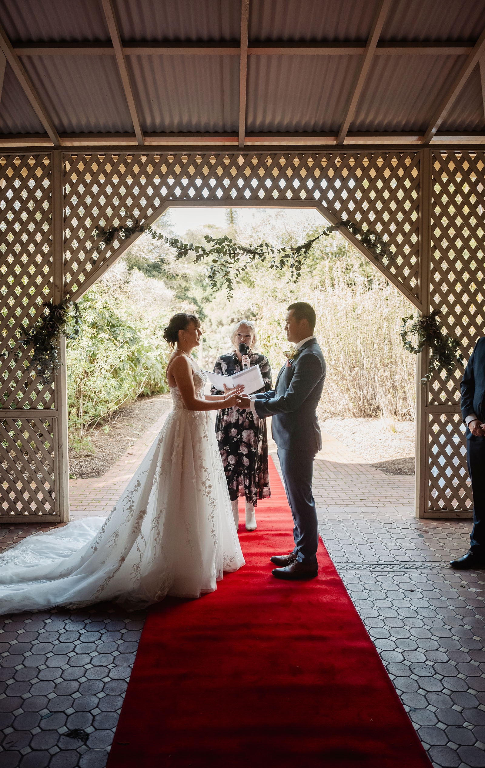 adelaide botanic gardens summerhouse wedding - belinda & ian 162 Elegant outdoor wedding ceremony with floral arrangements and guests under clear skies.