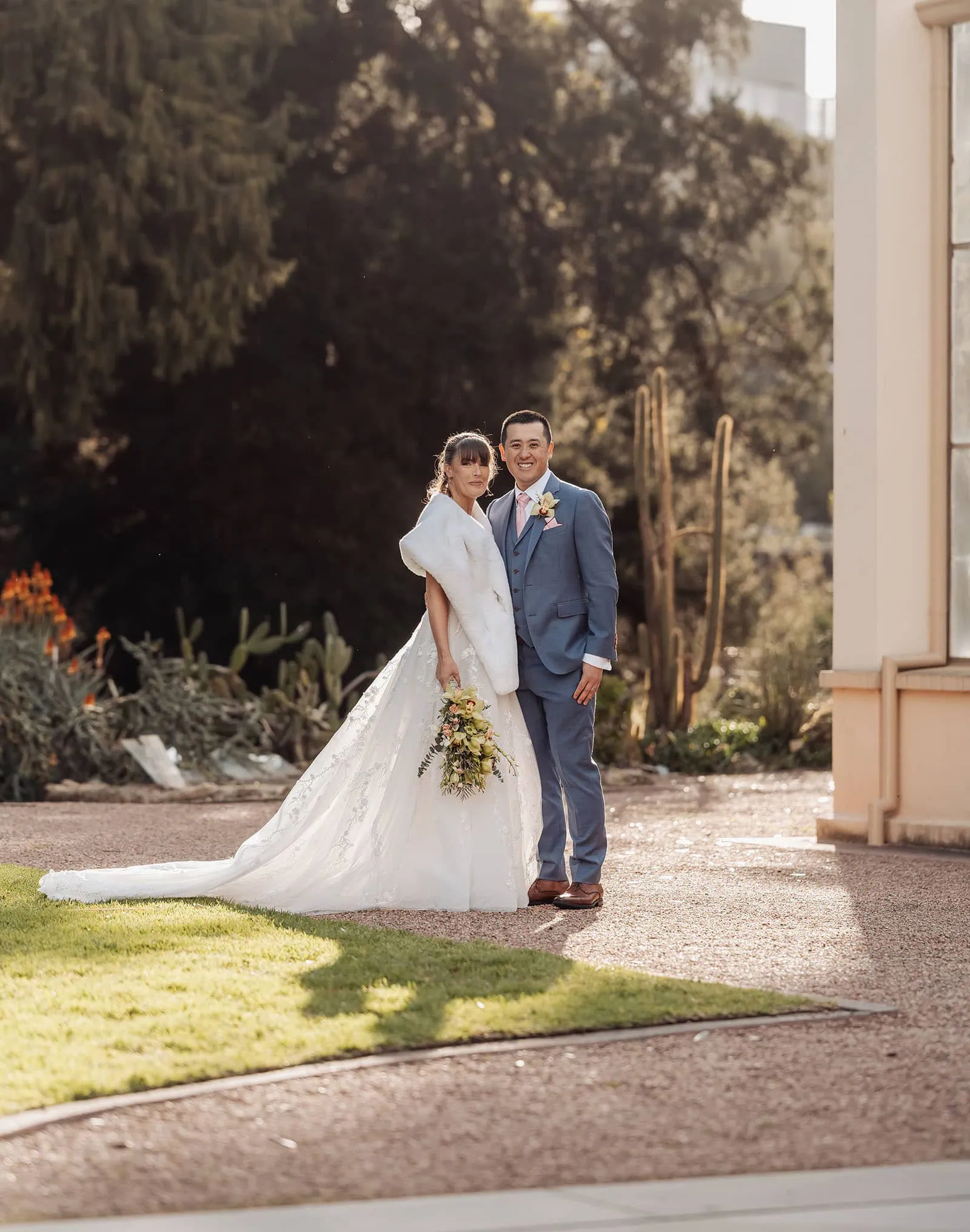 adelaide botanic gardens summerhouse wedding - belinda & ian 181 Bride and groom embrace under a vibrant outdoor wedding arch.