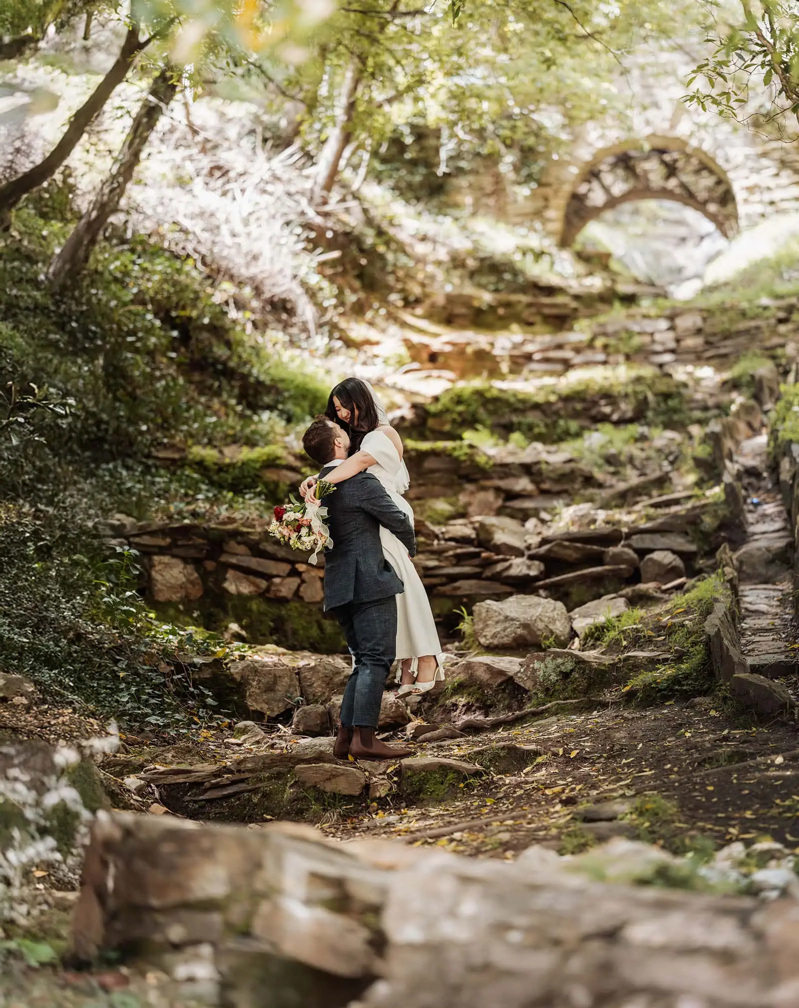 utopia waterfall gully wedding - sally & ben 248 A romantic couple strolling in a lush garden, surrounded by vibrant flowers and greenery.