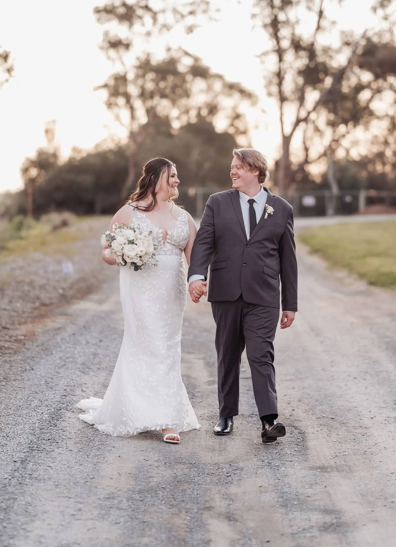 beach rd wines wedding - hana & jessie 85 Couple strolling romantically through scenic nature trail at sunset.