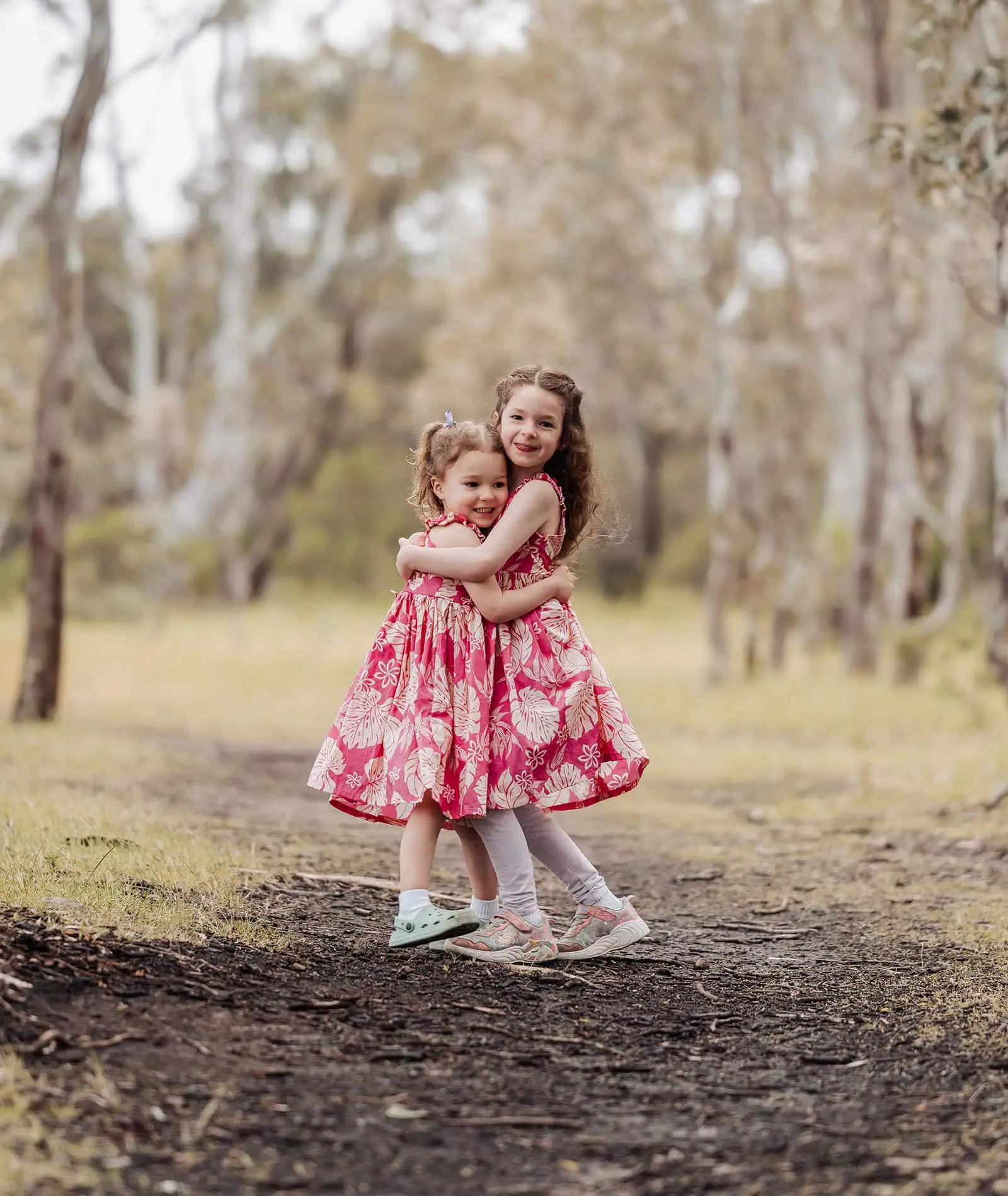 happy valley reservoir family photoshoot 1 Sisters walking a woodland path, surrounded by lush trees and natures serenity.