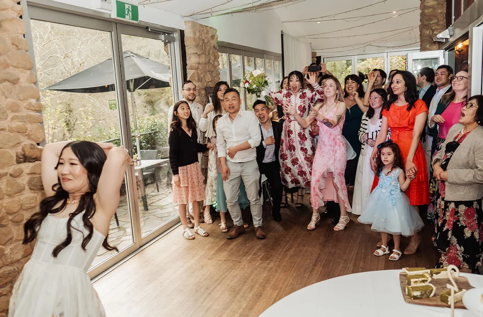 utopia waterfall gully wedding - sally & ben 271 Bride tossing bouquet to eager guests at wedding celebration.