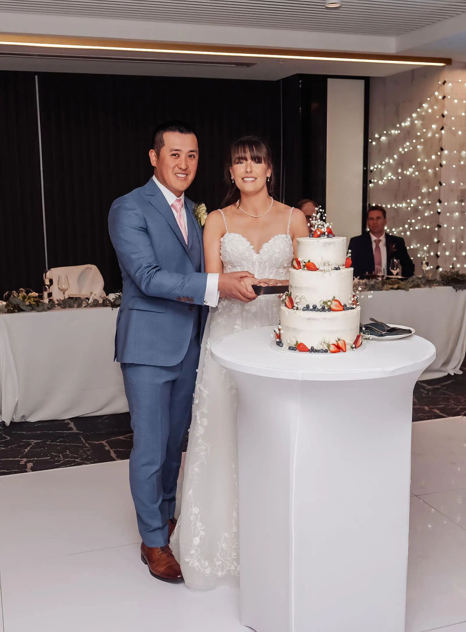 adelaide botanic gardens summerhouse wedding - belinda & ian 202 Bride and groom cutting elegant wedding cake during joyful reception ceremony.