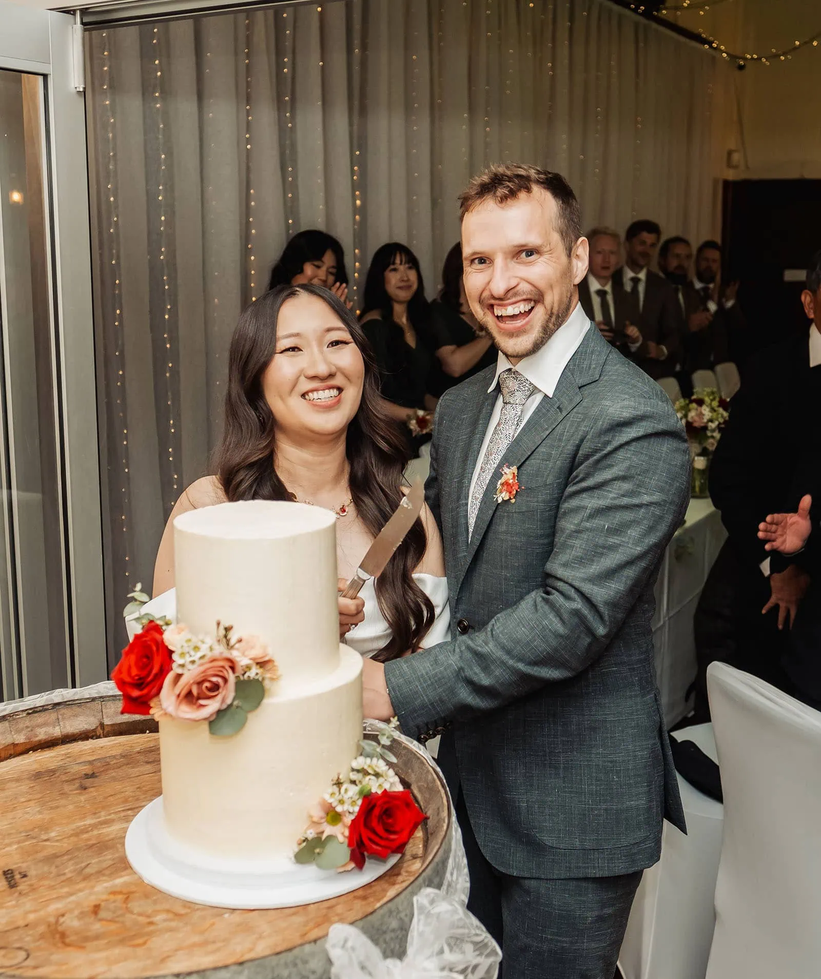 utopia waterfall gully wedding - sally & ben 253 Couple cutting elegant wedding cake, symbolizing unity and celebration.