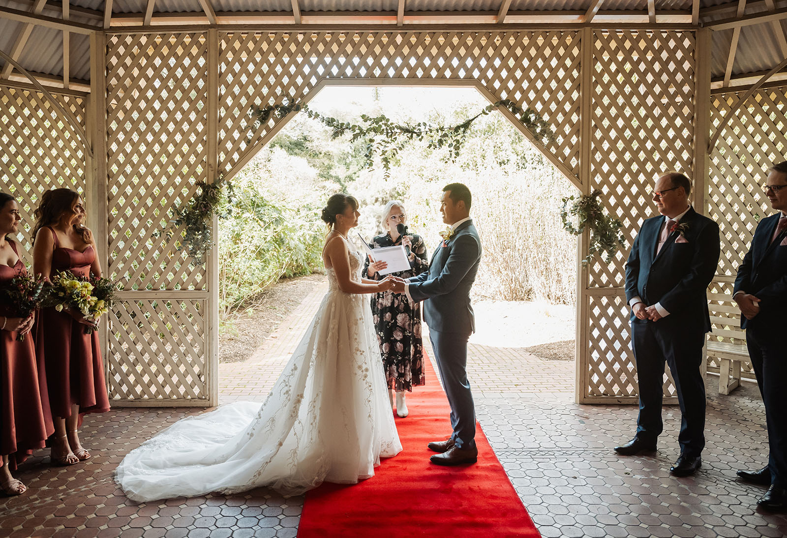 adelaide botanic gardens summerhouse wedding - belinda & ian 164 Outdoor wedding ceremony under elegant gazebo, decorated with flowers.