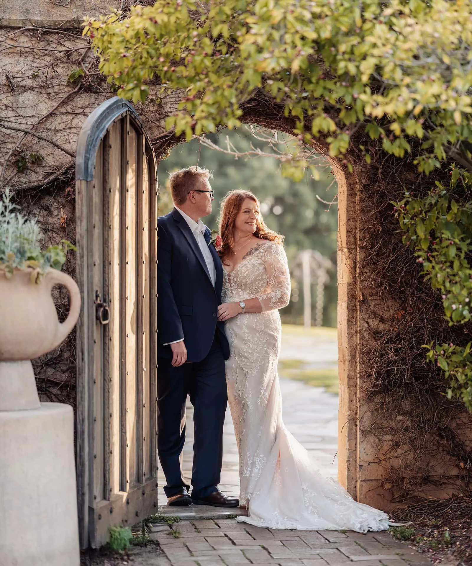 carrick hill wedding - jo & david 300 Bride and groom stand under floral archway during outdoor wedding ceremony.