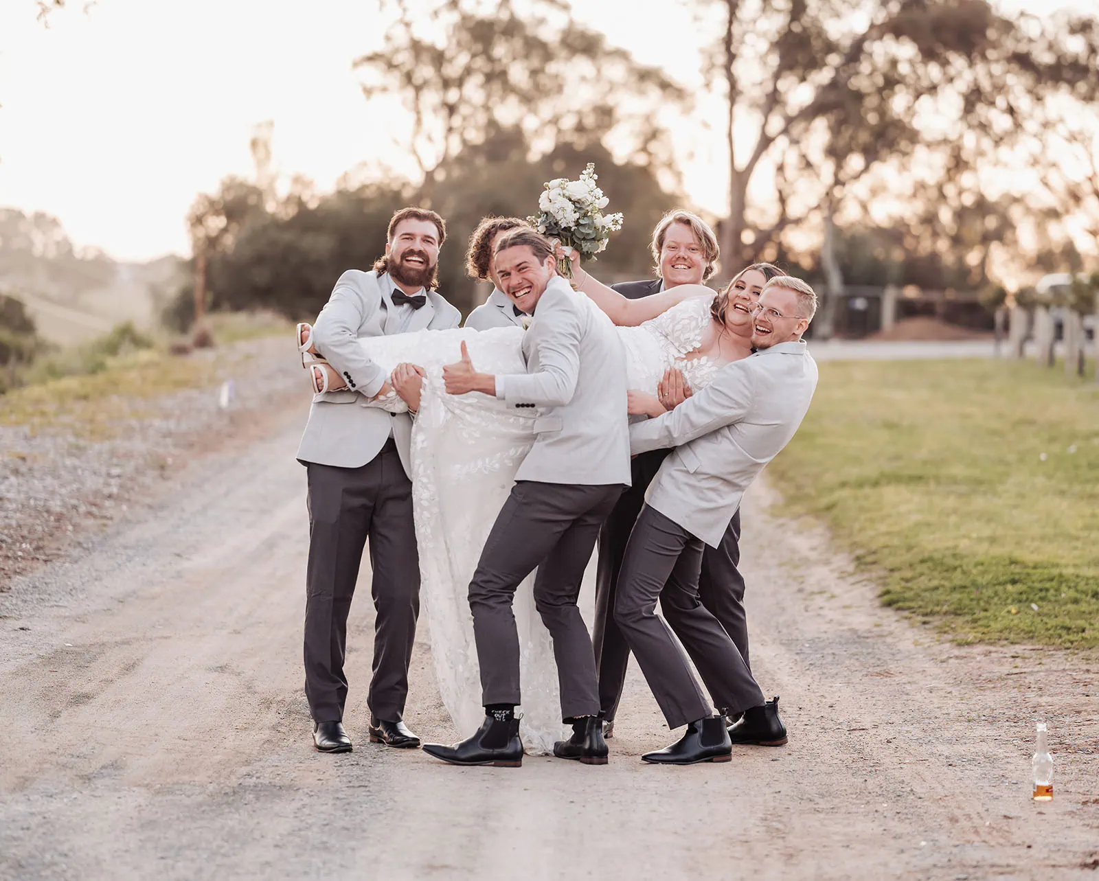 beach rd wines wedding - hana & jessie 84 Wedding party joyfully lifts couple in celebration.