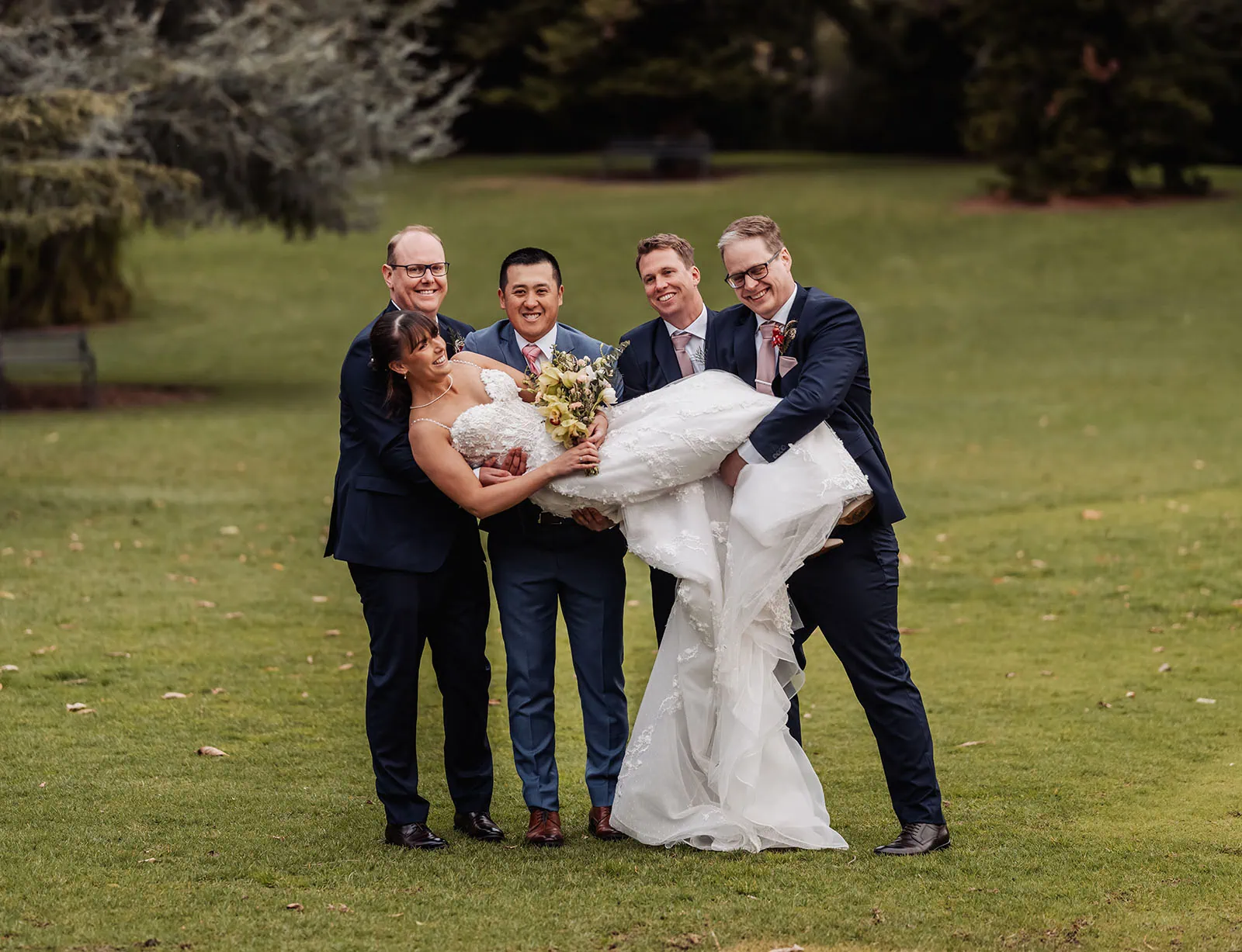 adelaide botanic gardens summerhouse wedding - belinda & ian 194 Joyful wedding party celebrating with laughter and happiness outdoors.
