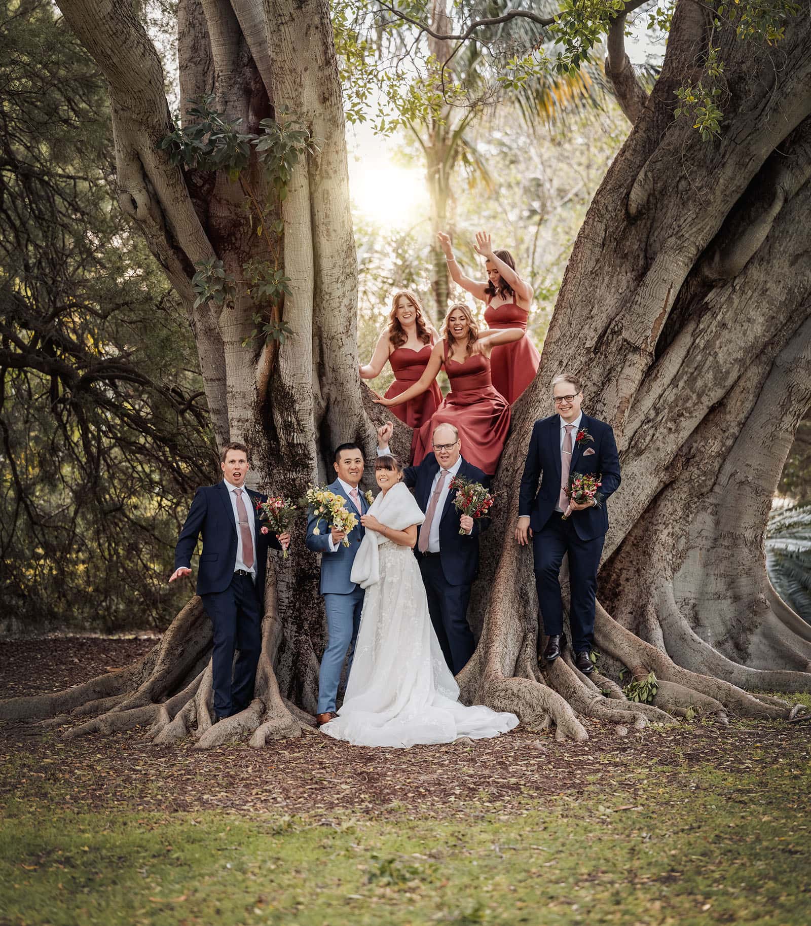 adelaide botanic gardens summerhouse wedding - belinda & ian 197 Bride and groom with wedding party under a large tree.