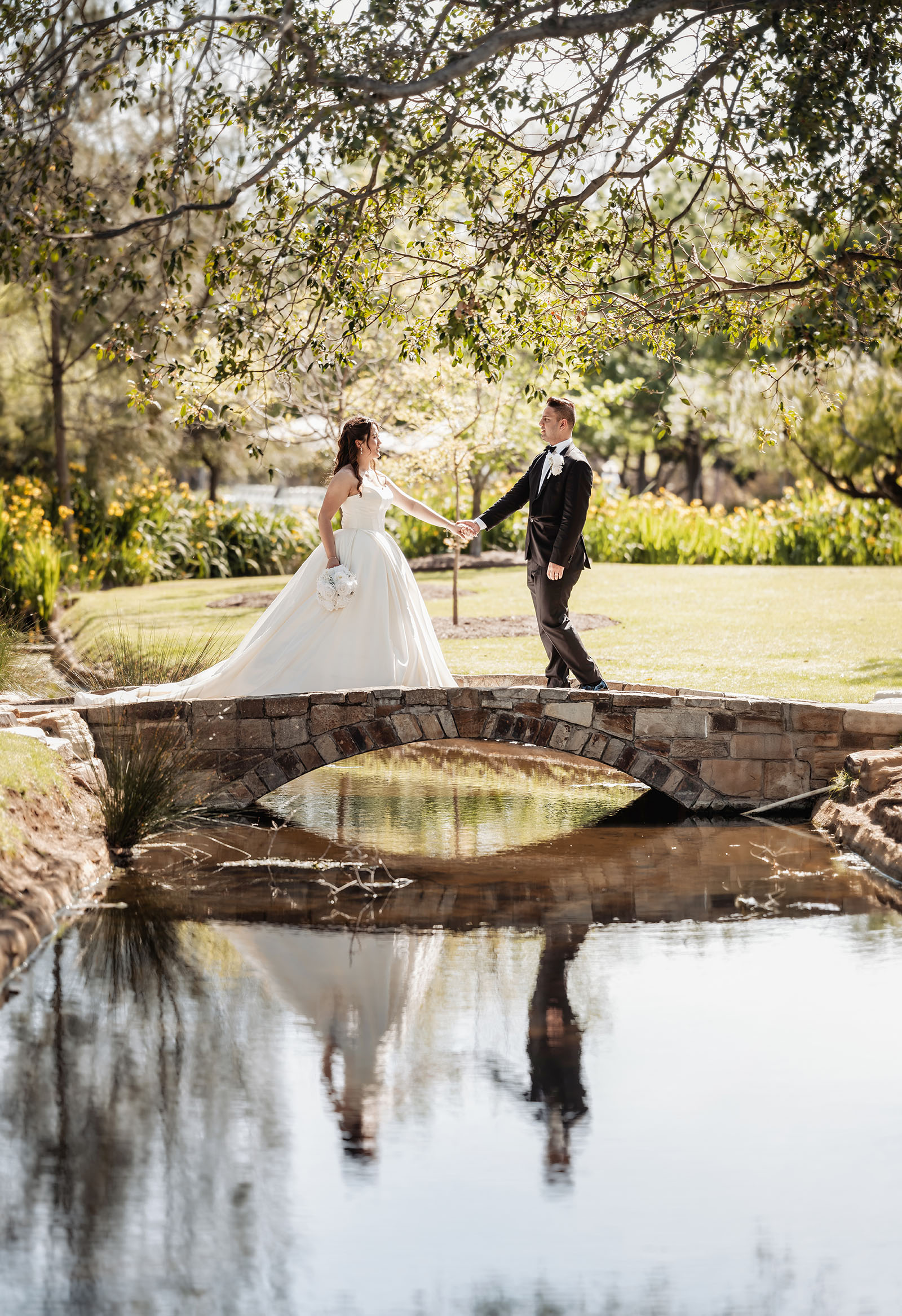 sunnybrae rose garden wedding - celina & anuj 59 Bride and groom pose romantically on a picturesque stone bridge.