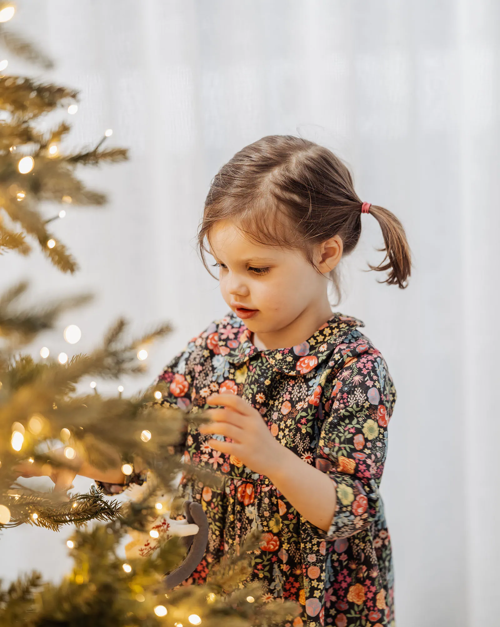 goodwood family photoshoot 109 Child decorating Christmas tree with ornaments and lights.