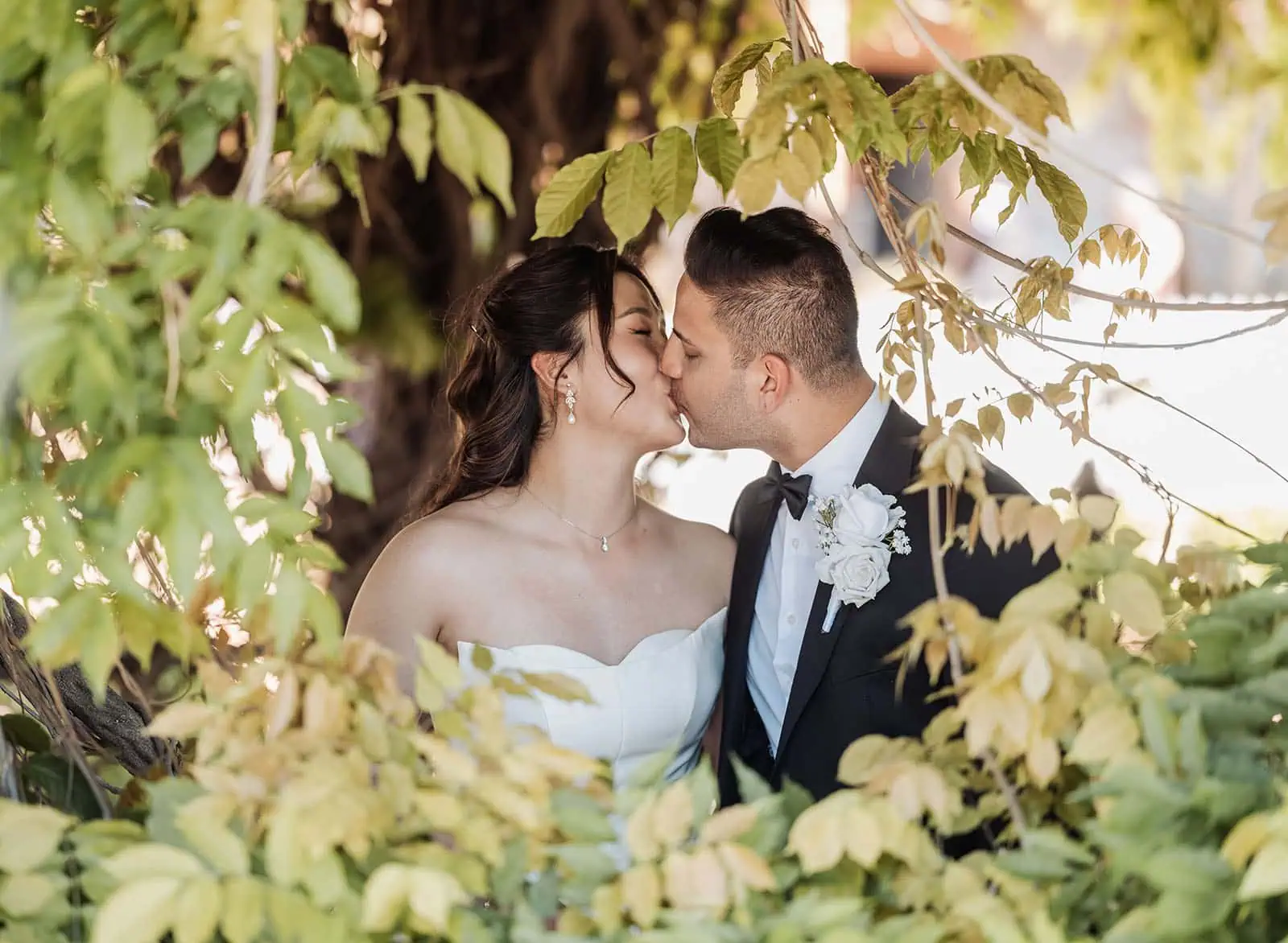 sunnybrae rose garden wedding - celina & anuj 52 Couple sharing a romantic kiss outdoors in a serene nature setting.