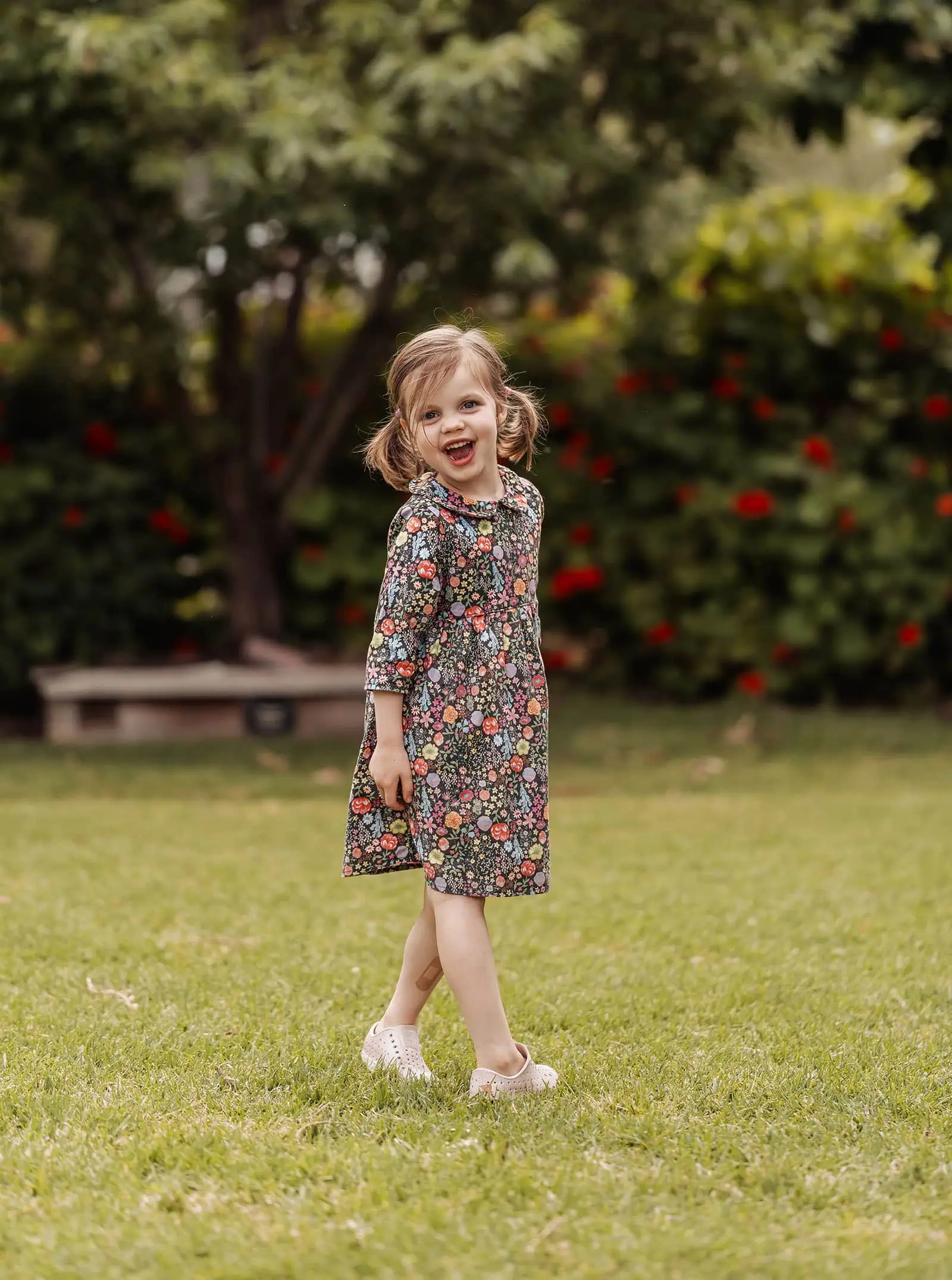 goodwood family photoshoot 122 Smiling girl enjoys lush garden surrounded by vibrant flowers.