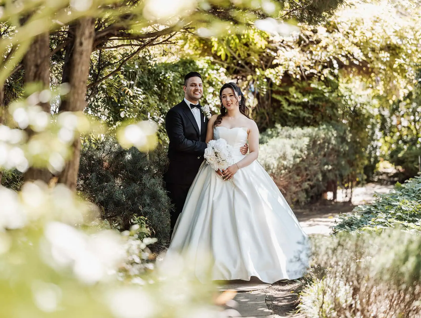 sunnybrae rose garden wedding - celina & anuj 25 Newlyweds embrace in a romantic garden setting, celebrating love amidst blooming flowers.