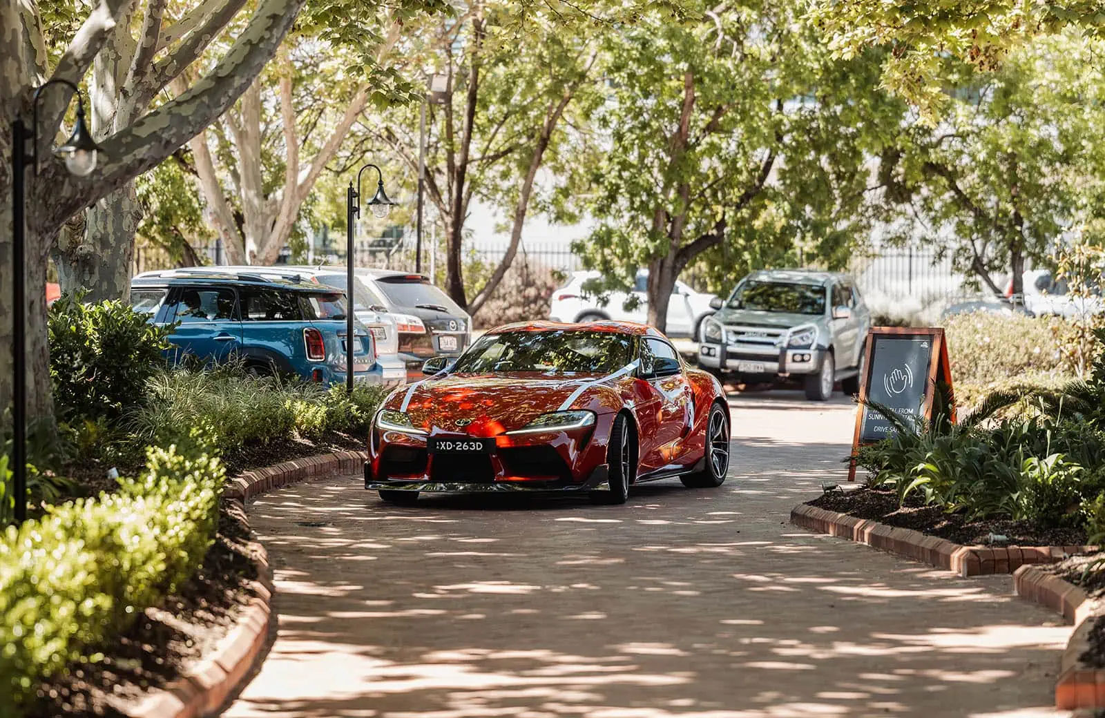 sunnybrae rose garden wedding - celina & anuj 41 Red sports car parked on scenic path near park.