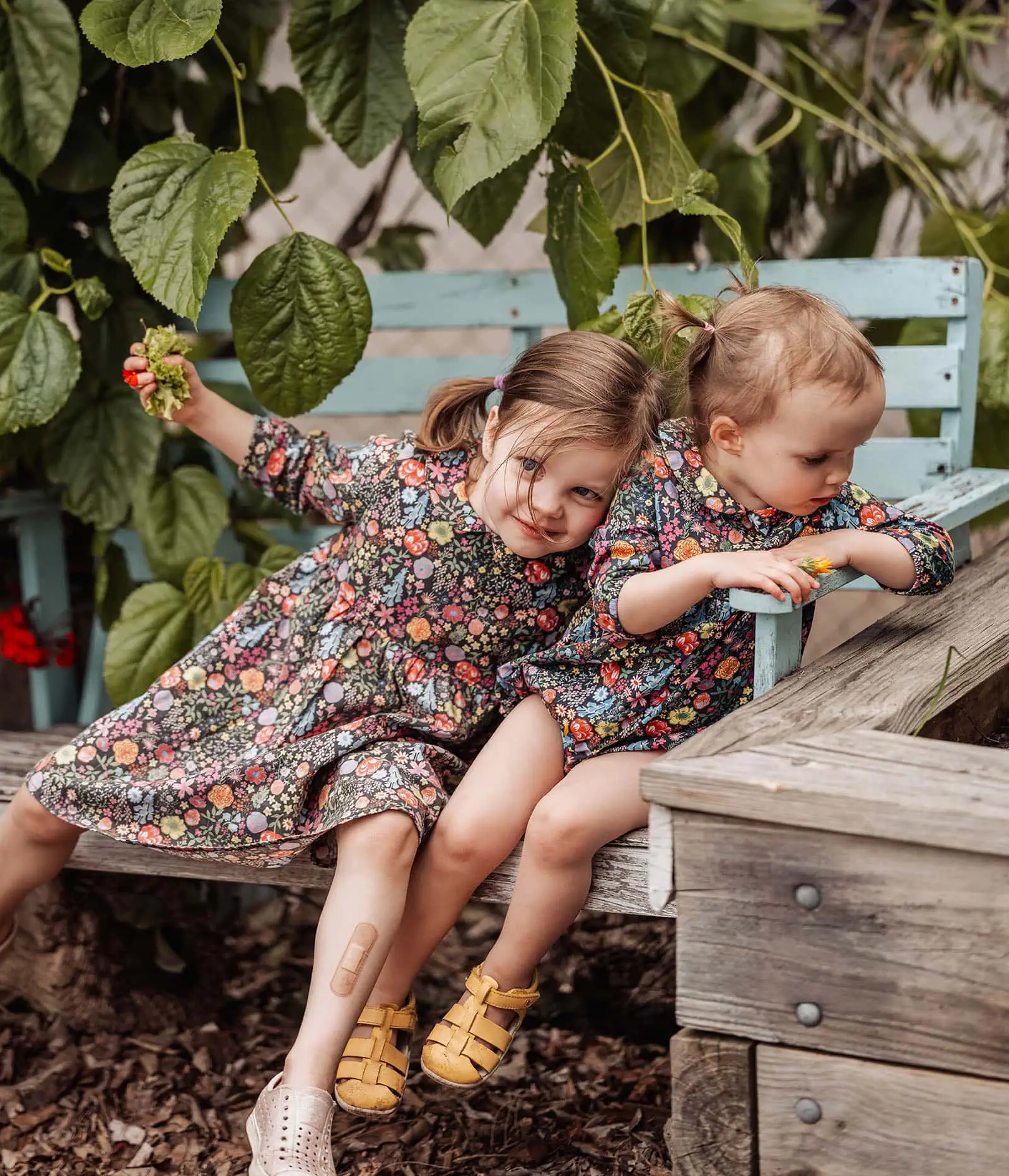 goodwood family photoshoot 125 Two sisters laughing together on a park bench.
