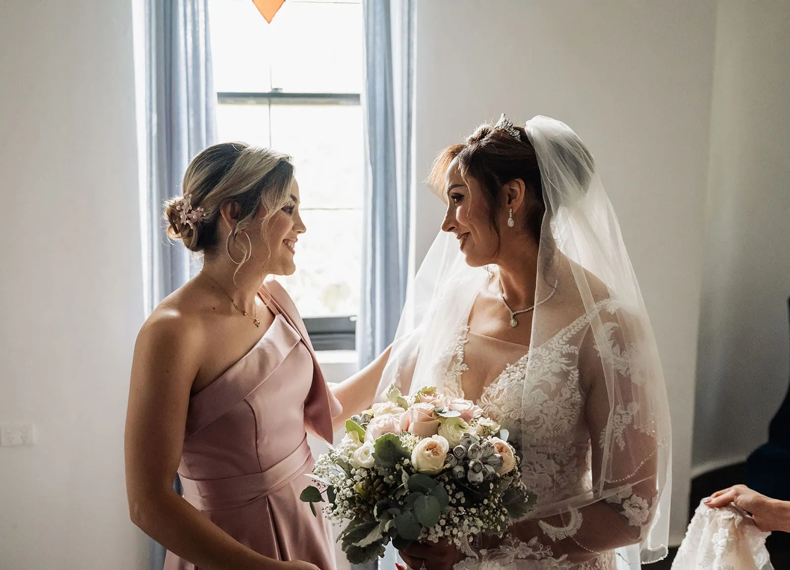 wedding at the manor in basket range - maryam & jason 130 Bride and bridesmaid sharing a joyful moment before wedding ceremony.