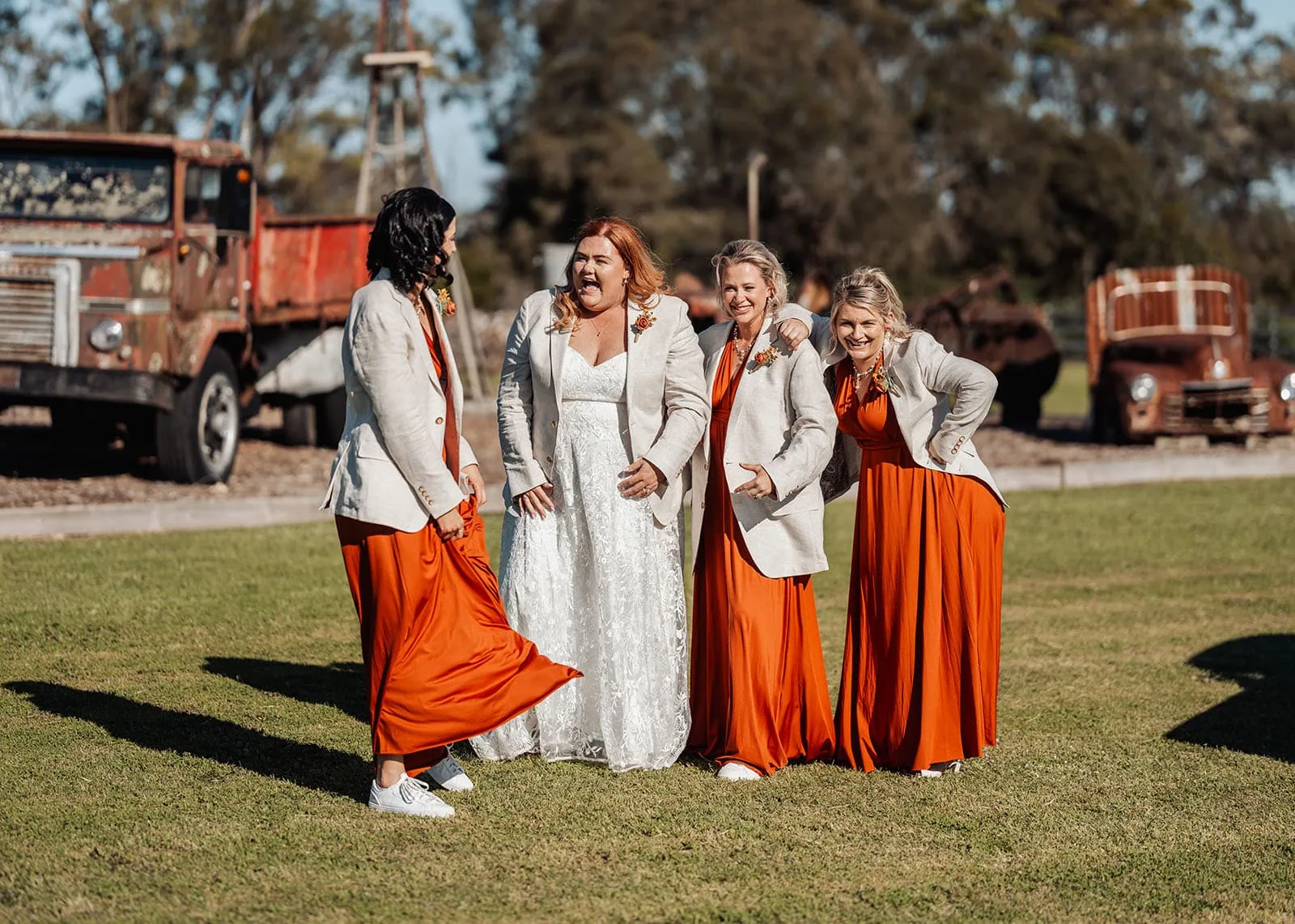 country victoria wedding in corrunnun – rachelle & anthony 345 Bride and bridesmaids pose with vintage trucks in elegant wedding attire.