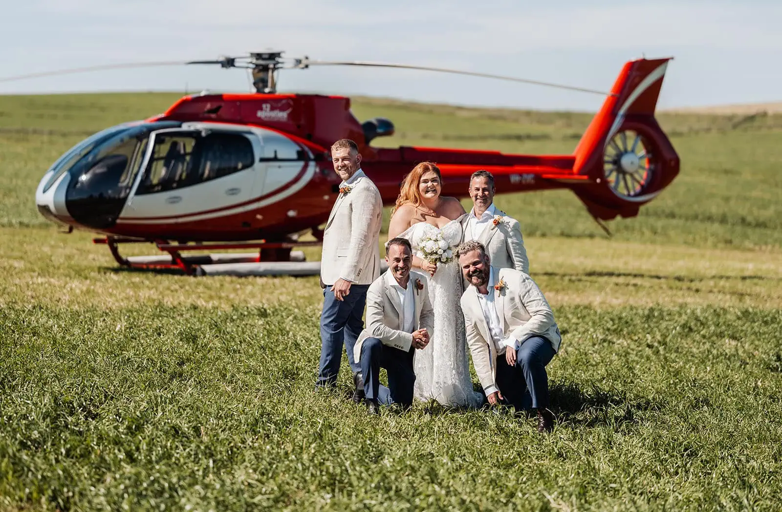 country victoria wedding in corrunnun – rachelle & anthony 332 Bride and groomsmen pose by helicopter at outdoor wedding.