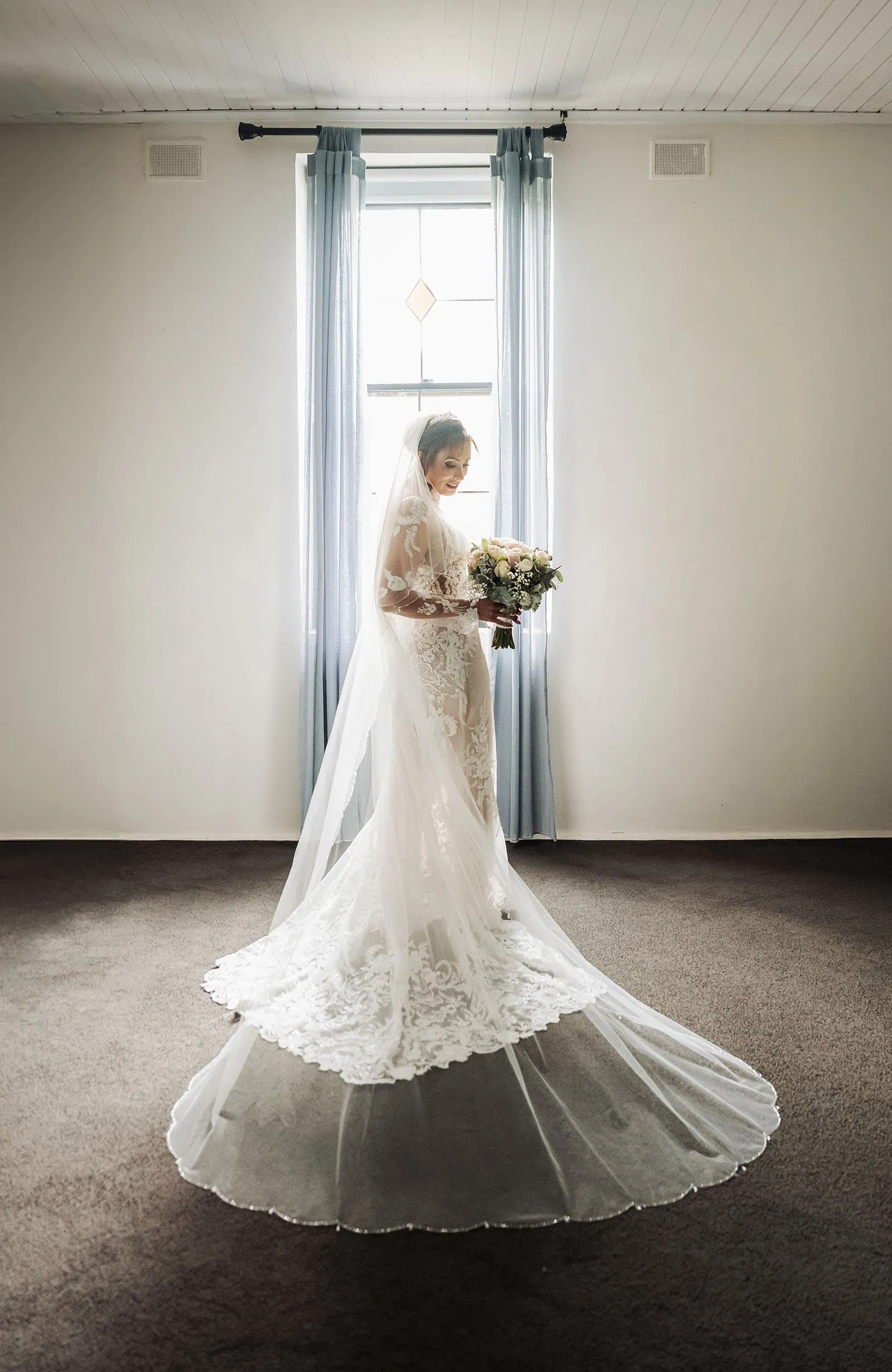 wedding at the manor in basket range - maryam & jason 126 Bride in a sunlit room, wearing a white dress, exuding elegance and joy.