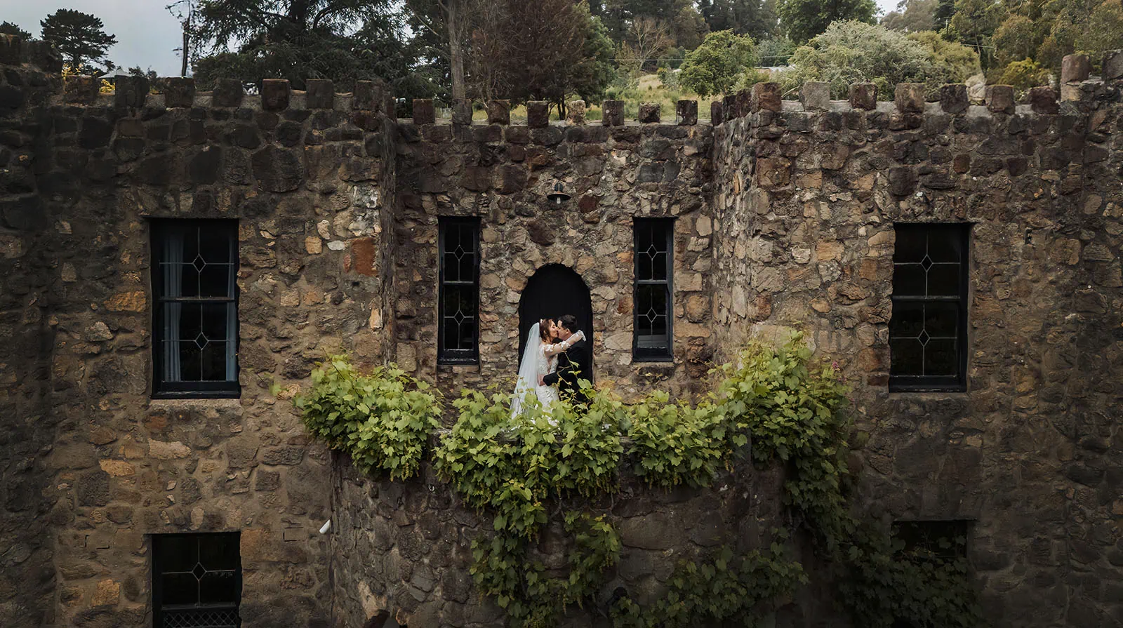 wedding at the manor in basket range - maryam & jason 145 Romantic sunset at a medieval castle with two embracing figures.