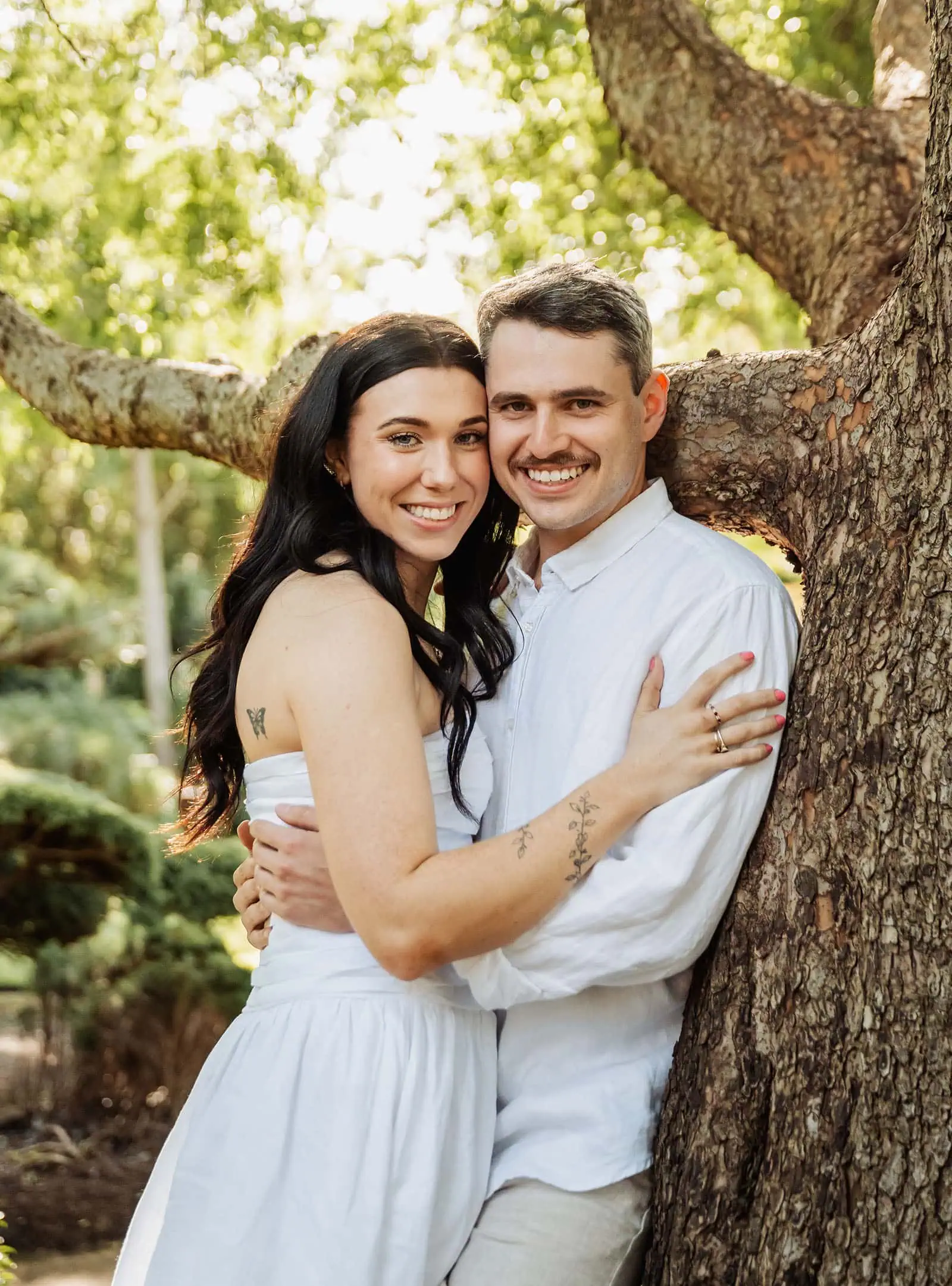 himeji gardens couples shoot - tom & tess 103 Couple embracing under a tree in a romantic, serene nature setting.