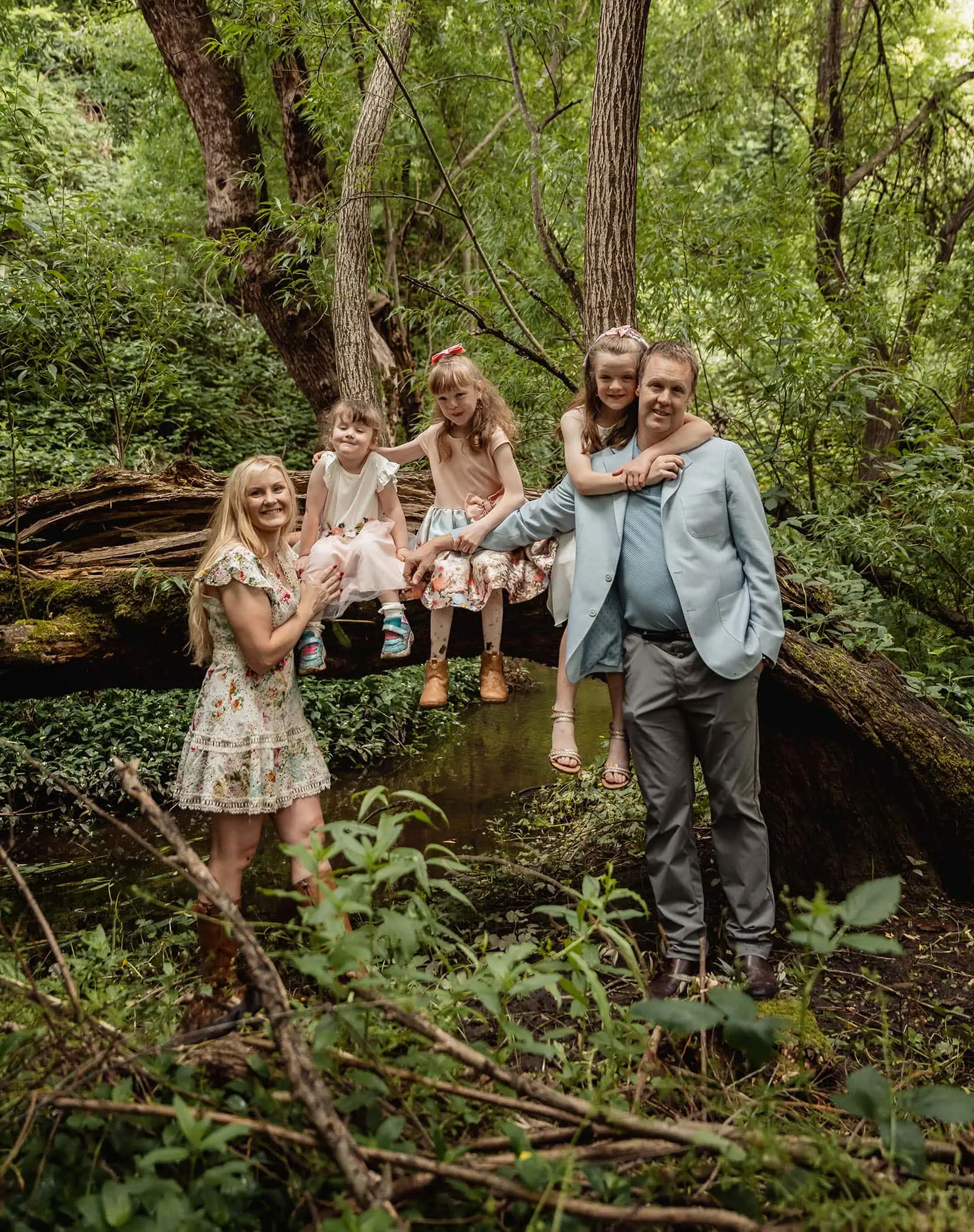 ironbank family photography 121 Family enjoying nature in forest with children on log, surrounded by vibrant greenery.