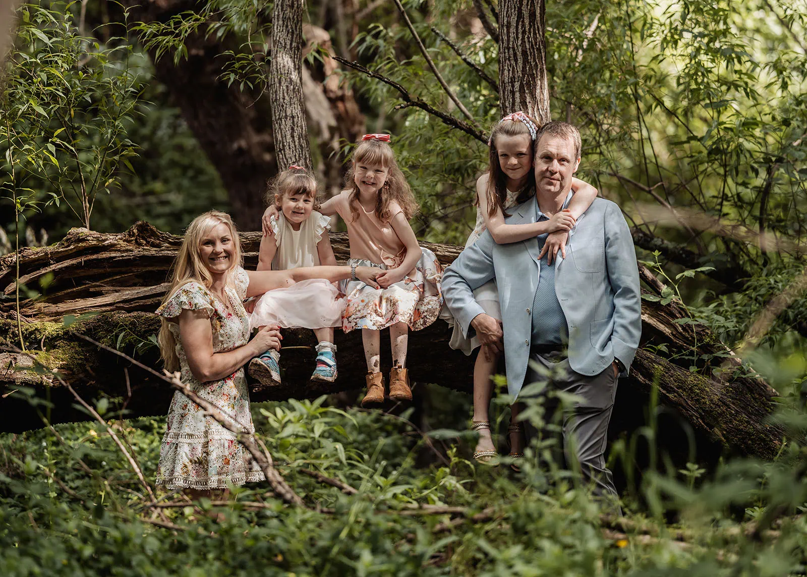 ironbank family photography 119 Family enjoying a serene forest moment on a fallen tree, bathed in warm sunlight.