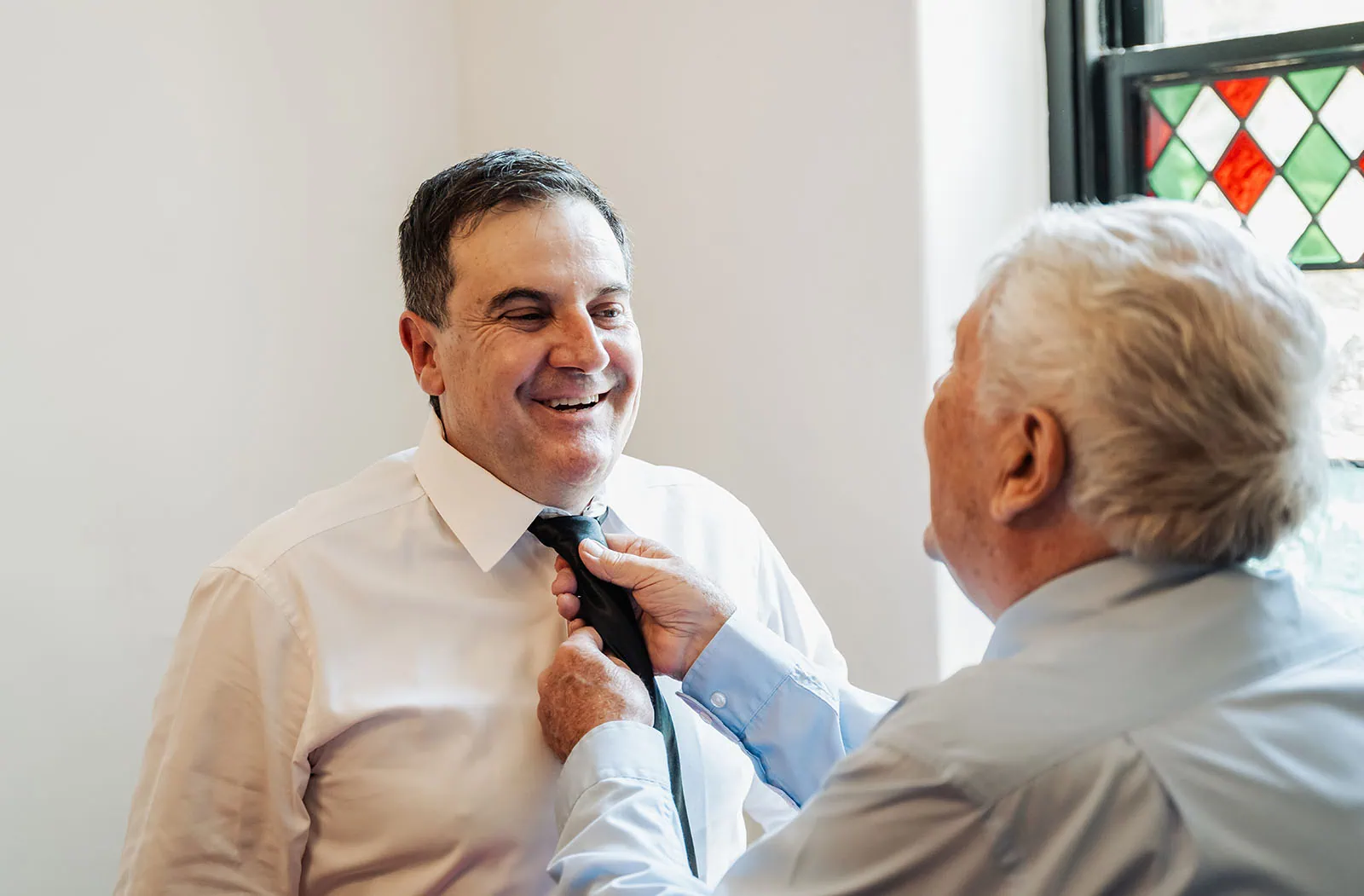 wedding at the manor in basket range - maryam & jason 115 Father and son bonding over tying a necktie at home.