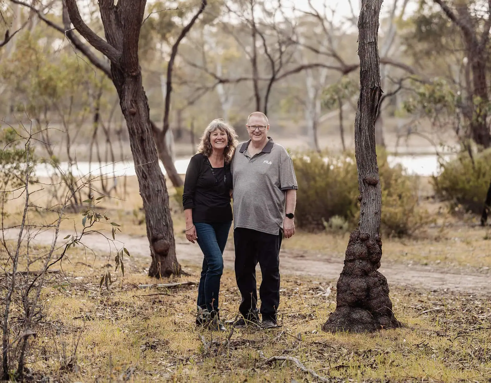 happy valley reservoir family shoot 97 Two people smiling in a serene forest, enjoying a tranquil nature walk.