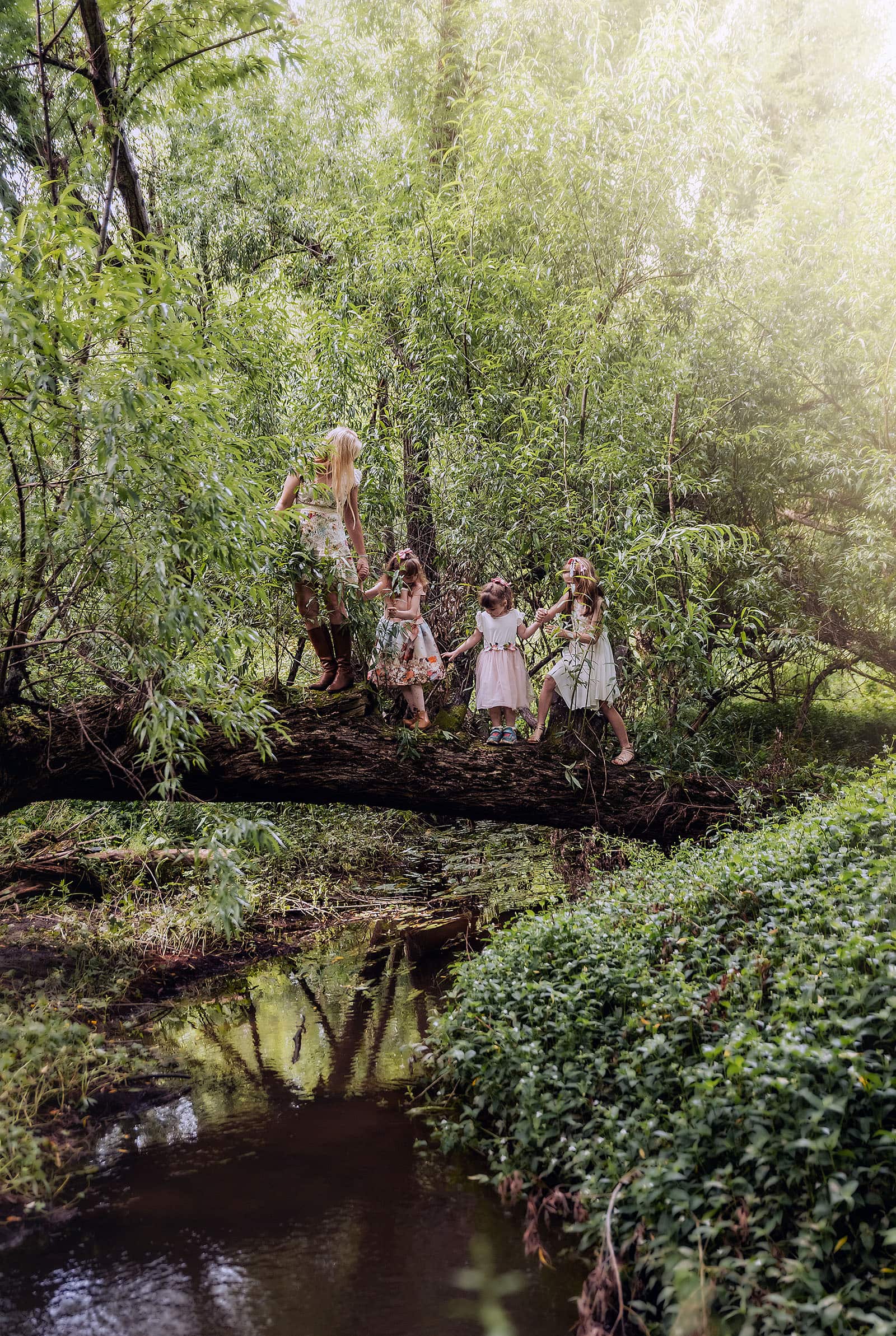 ironbank family photography 127 Young girls crossing a forest creek, wearing floral dresses and flower crowns, exuding magic.