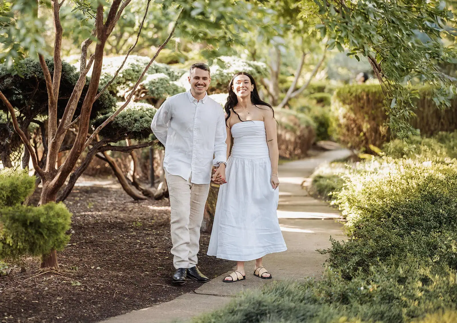 himeji gardens couples shoot - tom & tess 101 Couple walking through lush garden pathway, enjoying nature and tranquility.
