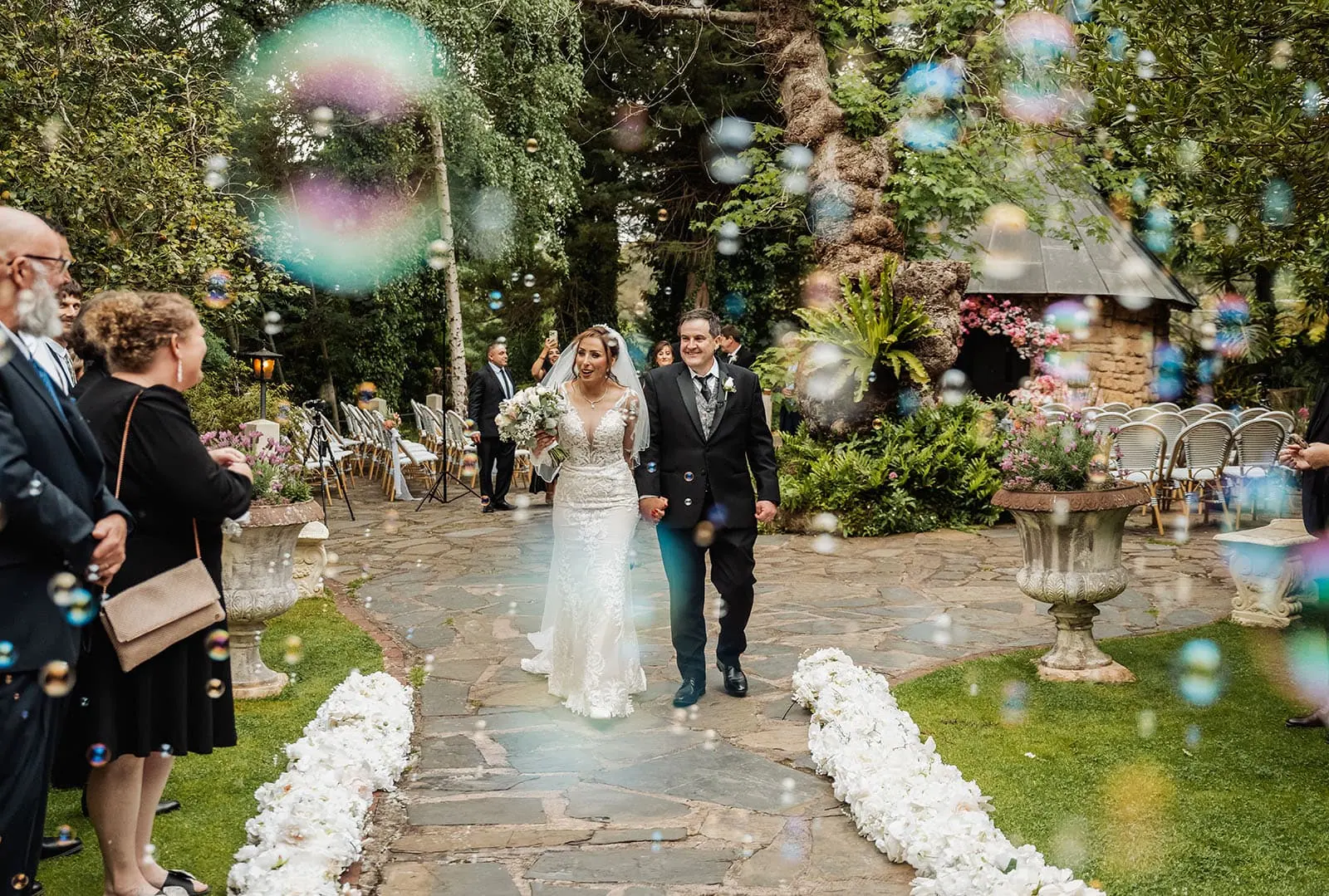 wedding at the manor in basket range - maryam & jason 139 Elegant garden wedding setup with floral decorations and white chairs.