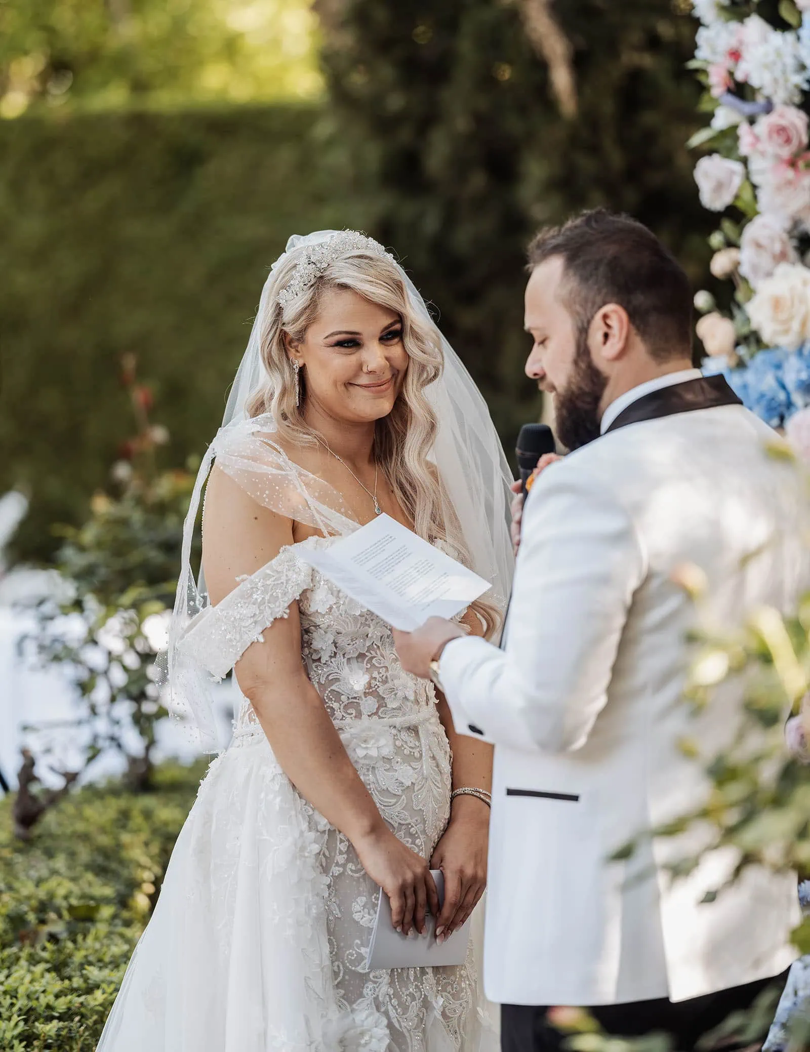 silvestris of clarendon wedding - sam & wayne 219 Romantic garden wedding vows under floral arch, couple exchanging promises outdoors.