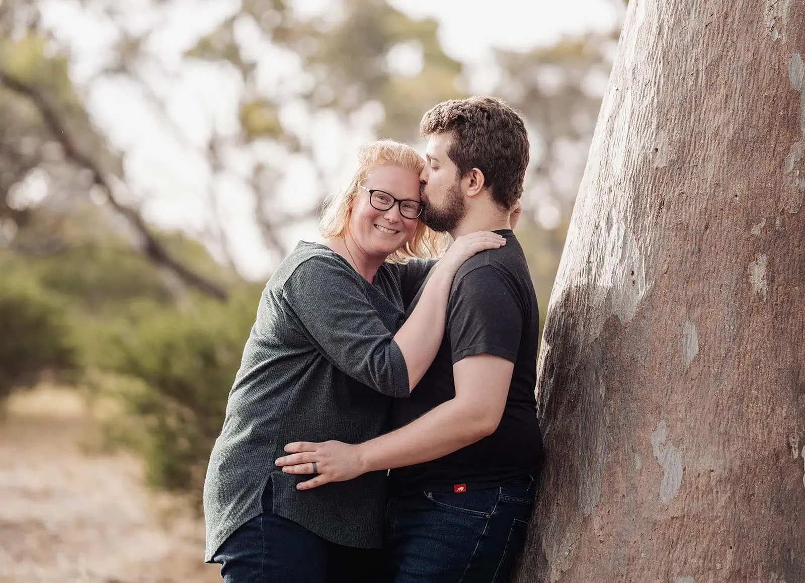 happy valley reservoir family shoot 88 Couple embracing under a tree in a serene park setting.