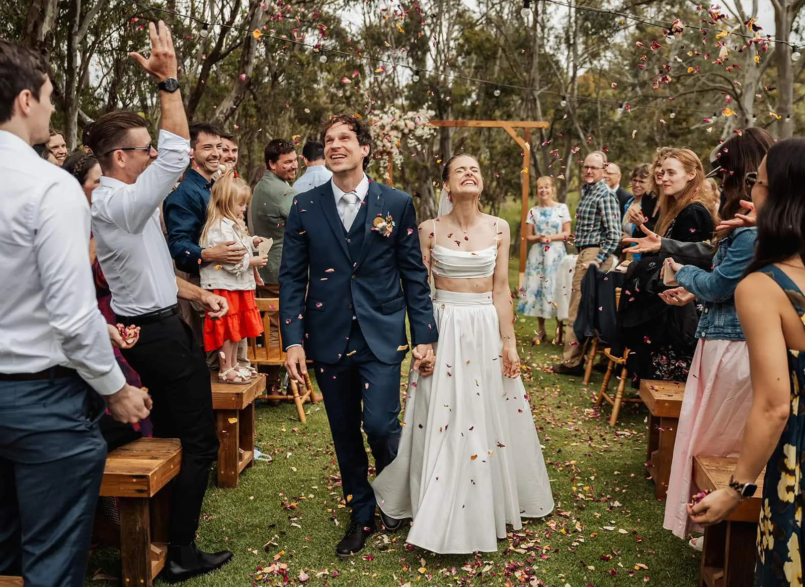 fleurieu cherries wedding - kimberley & richard 21 Scenic outdoor wedding aisle with floral decorations and chairs under a sunny sky.