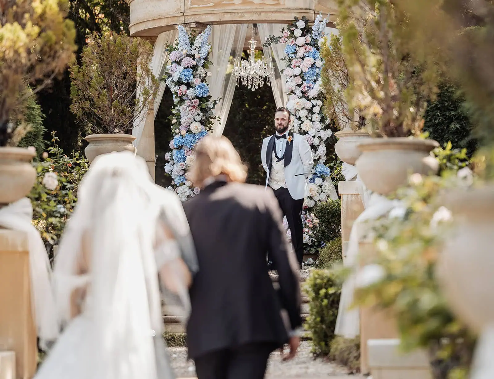 silvestris of clarendon wedding - sam & wayne 213 Elegant outdoor wedding ceremony with floral decorations and seating under clear blue sky.