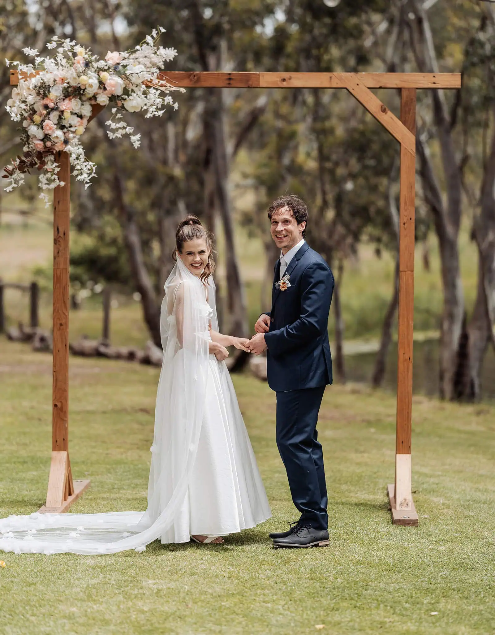 fleurieu cherries wedding - kimberley & richard 19 Elegant outdoor wedding ceremony under a floral arch with guests seated.