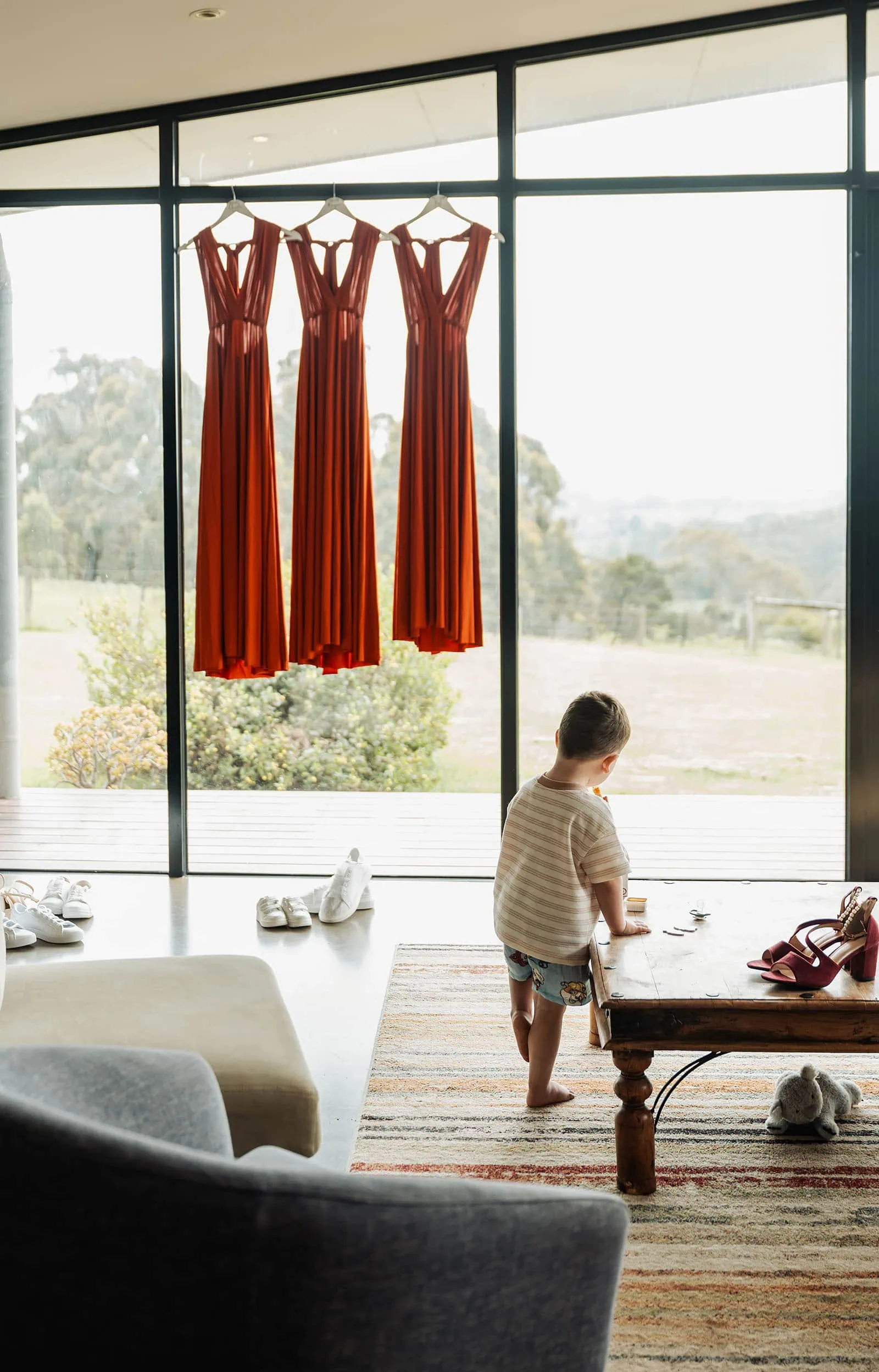 country victoria wedding in corrunnun – rachelle & anthony 299 Red dresses displayed elegantly by a sunlit window.