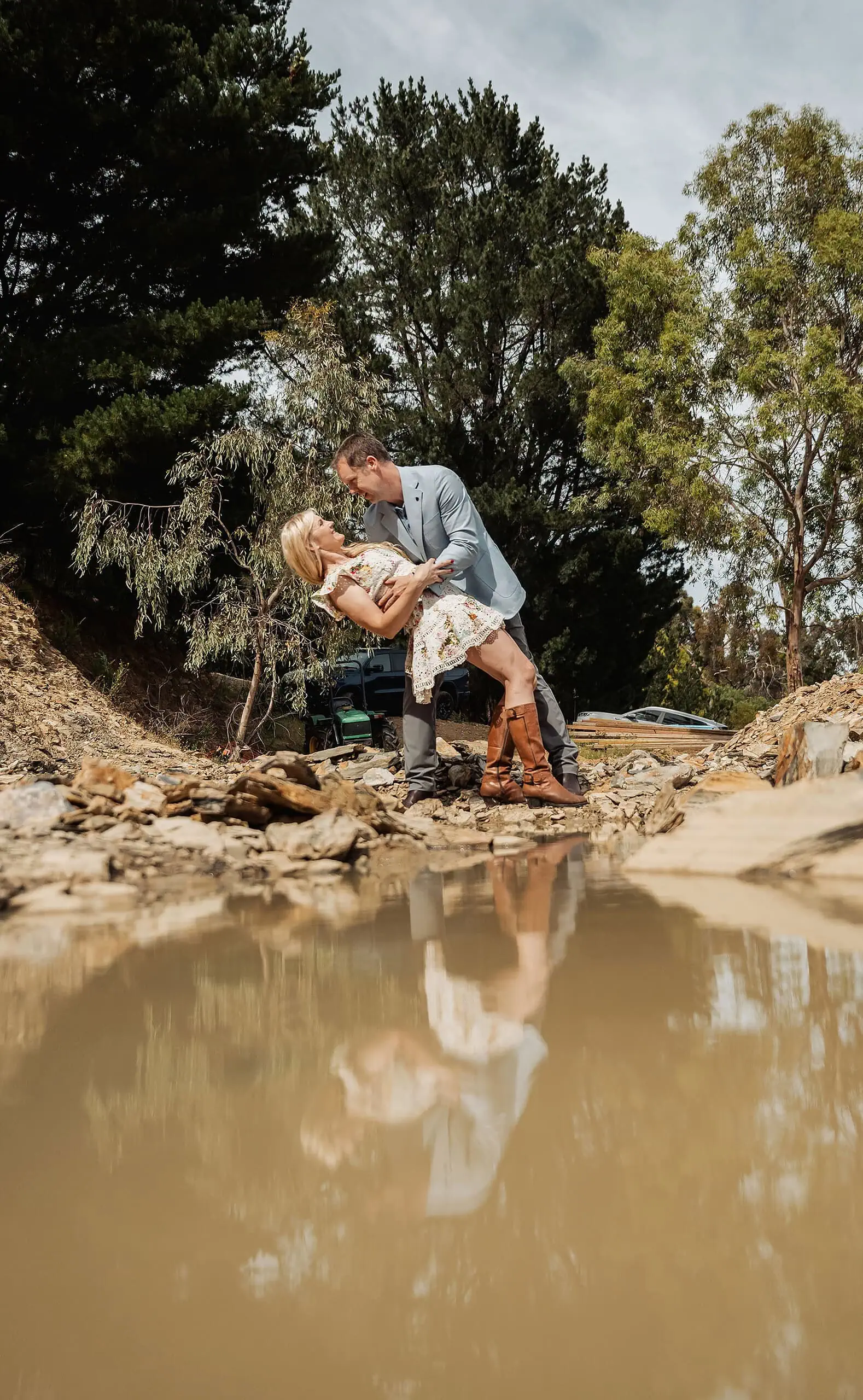 ironbank family photography 134 Couple enjoying a romantic dip on rocky terrain with forest backdrop and water reflection.