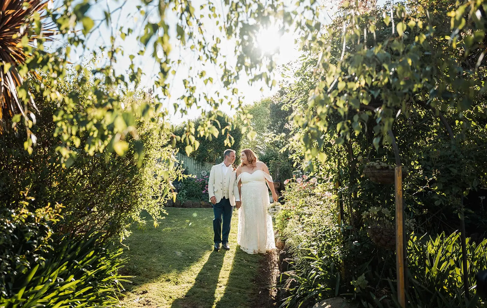 country victoria wedding in corrunnun – rachelle & anthony 356 Couple embracing in a lush, blooming garden.