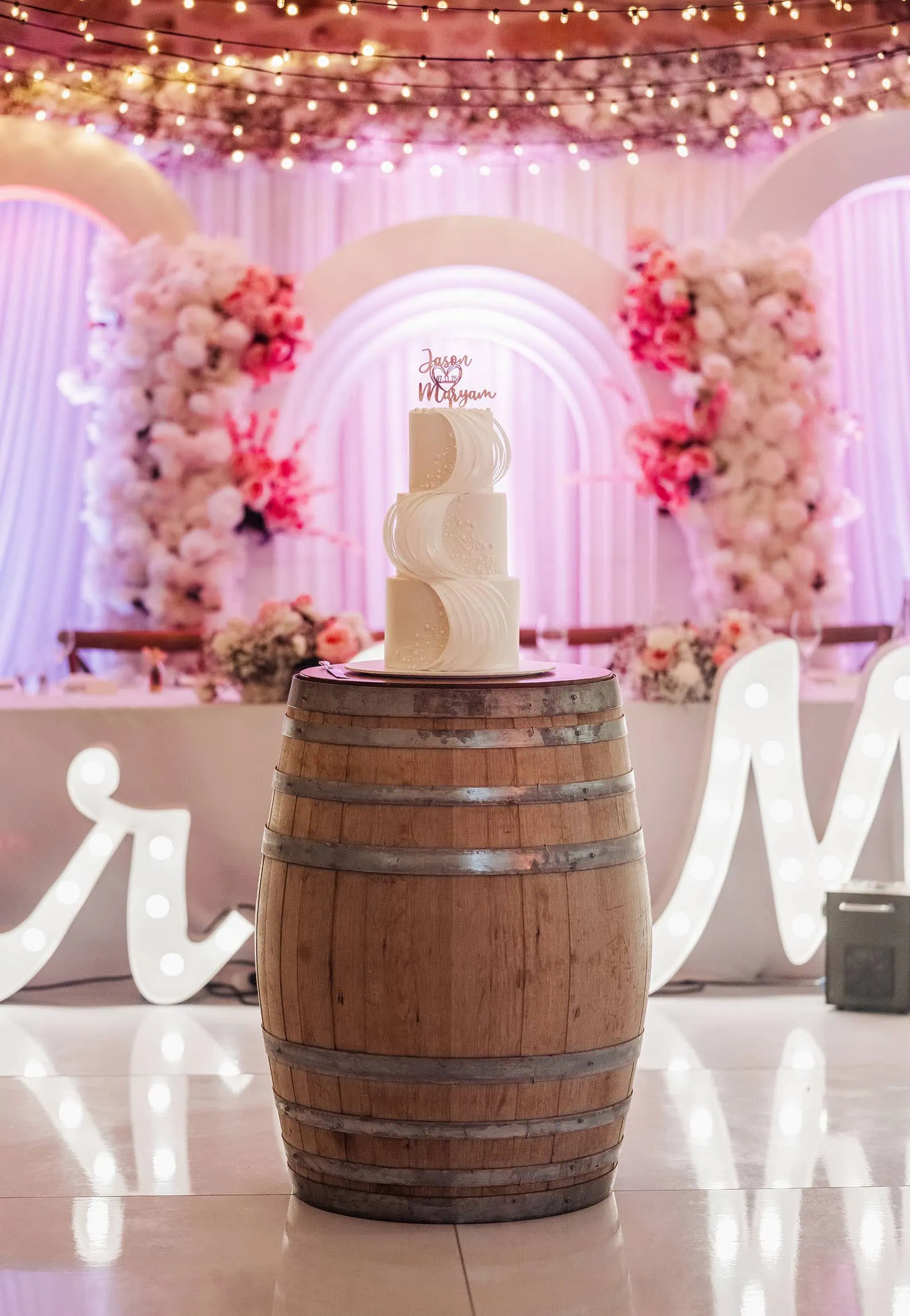 wedding at the manor in basket range - maryam & jason 148 Rustic tiered wedding cake on wooden display with floral accents.