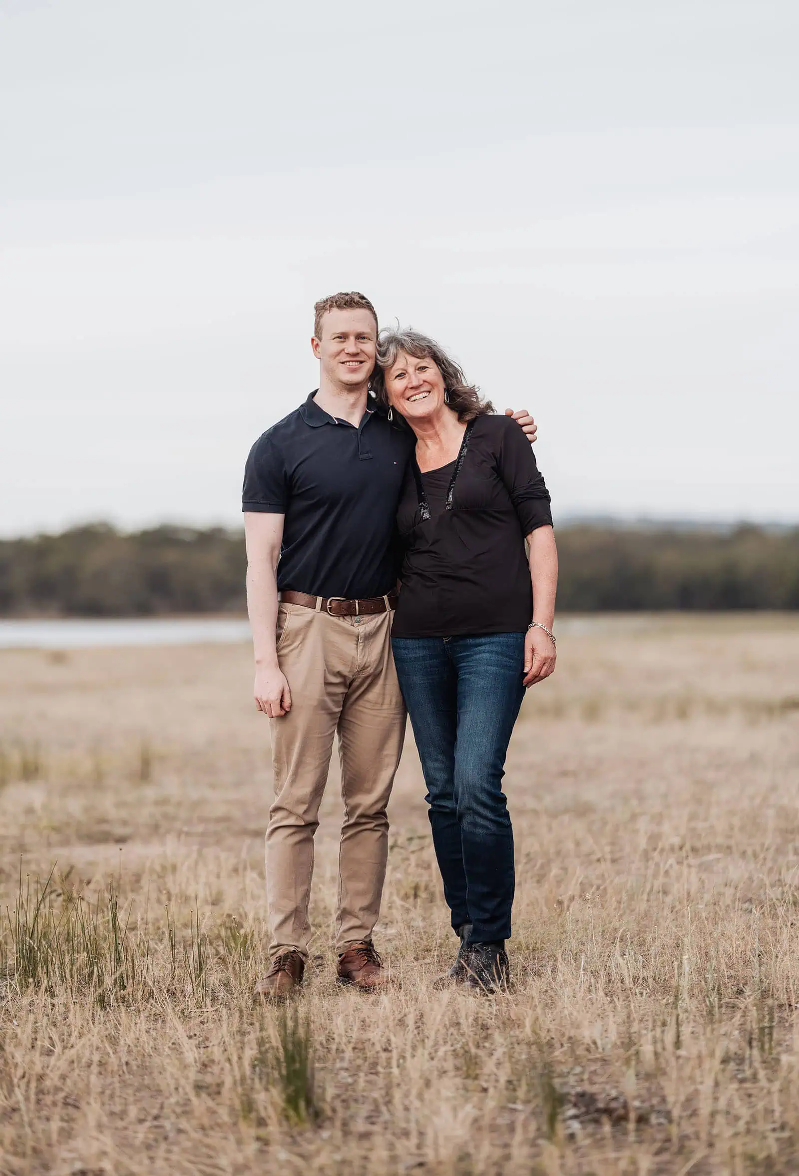 happy valley reservoir family shoot 106 Two friends sharing a joyful moment in an open field under overcast skies.