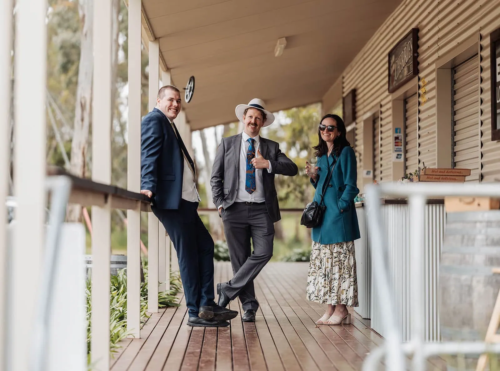 fleurieu cherries wedding - kimberley & richard 67 Friends chatting on a sunny veranda with green landscape views.