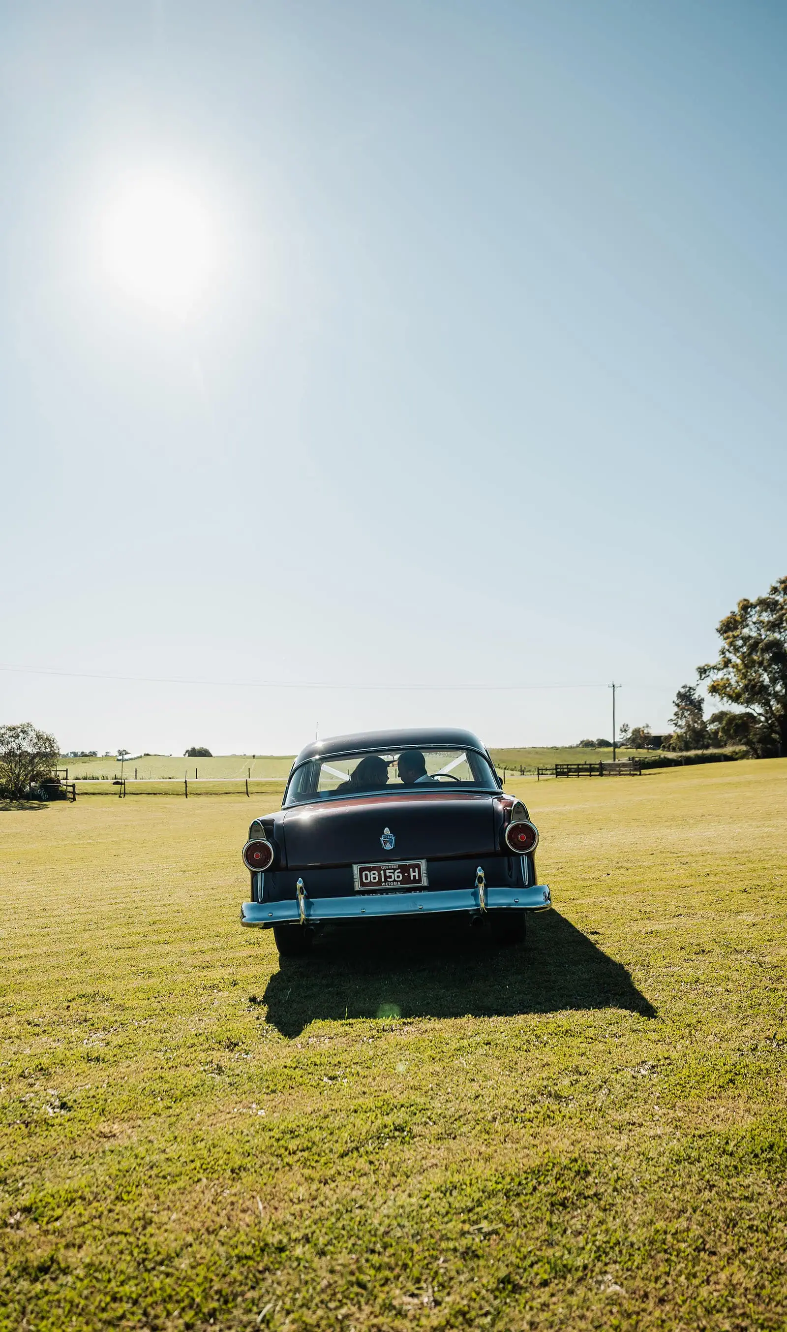 country victoria wedding in corrunnun – rachelle & anthony 347 Vintage car driving through scenic countryside landscape.