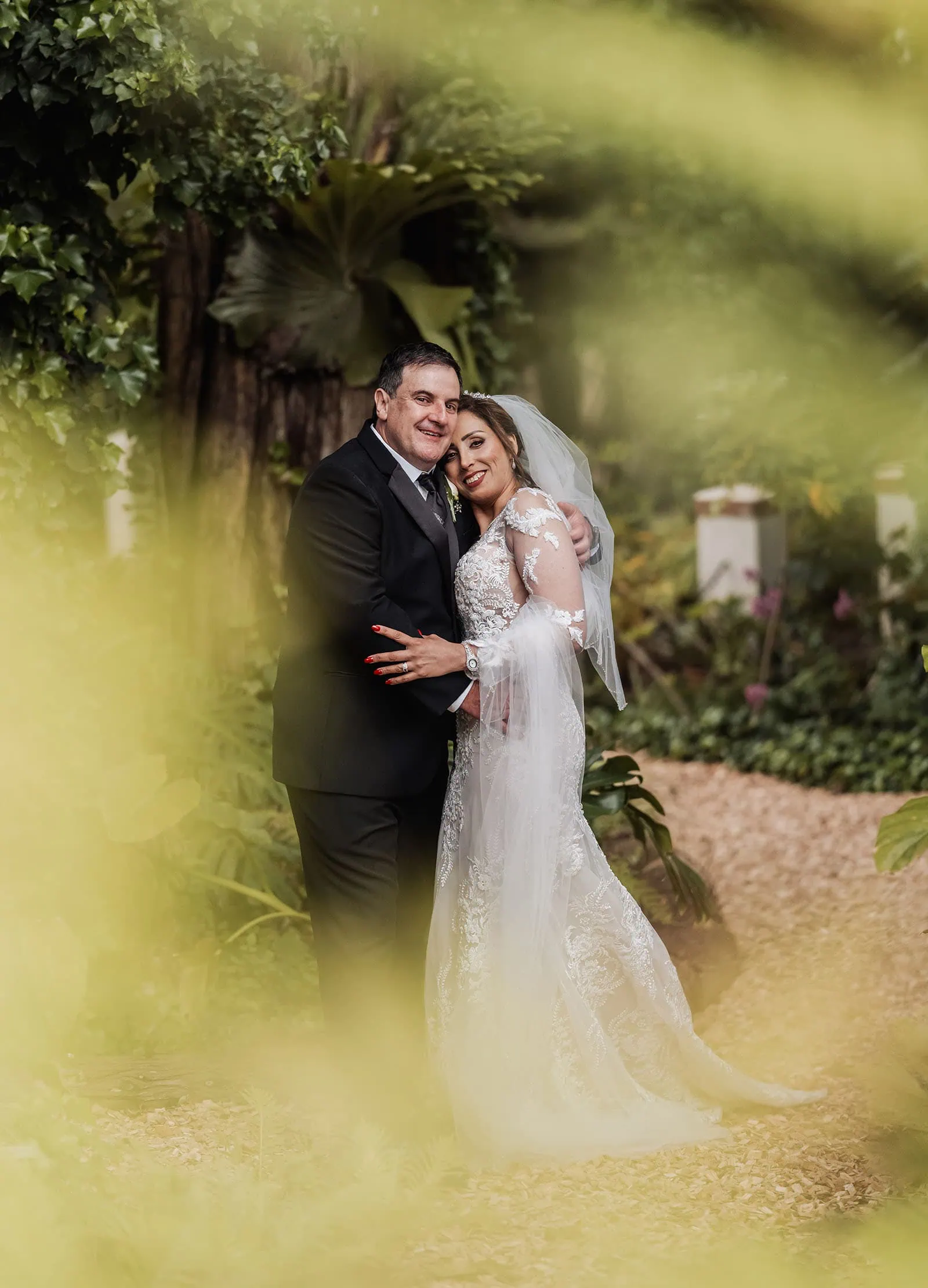 wedding at the manor in basket range - maryam & jason 146 Bride and groom pose elegantly in a lush garden setting.