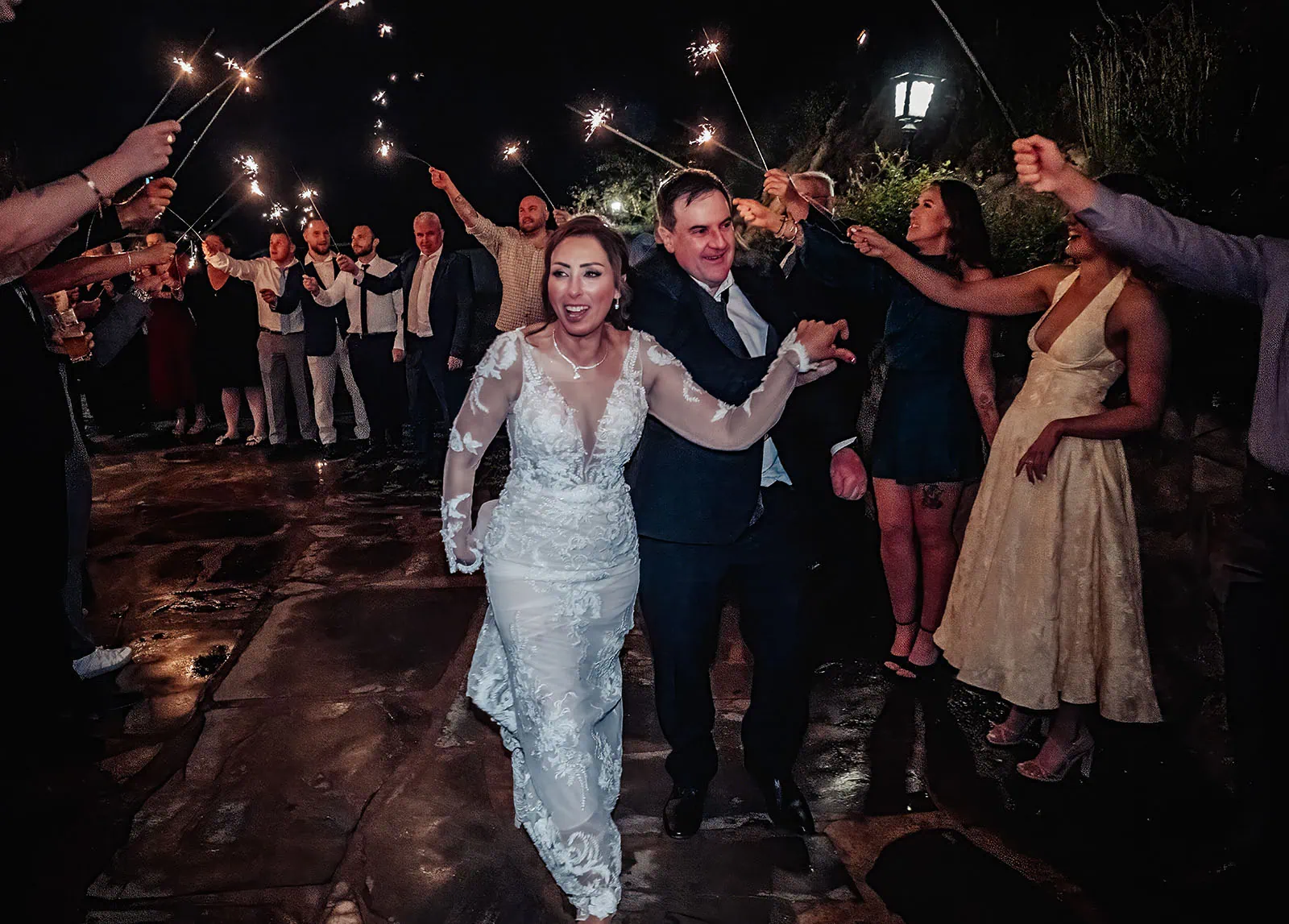 wedding at the manor in basket range - maryam & jason 178 Bride and groom exit wedding under sparkling lights with guests cheering.