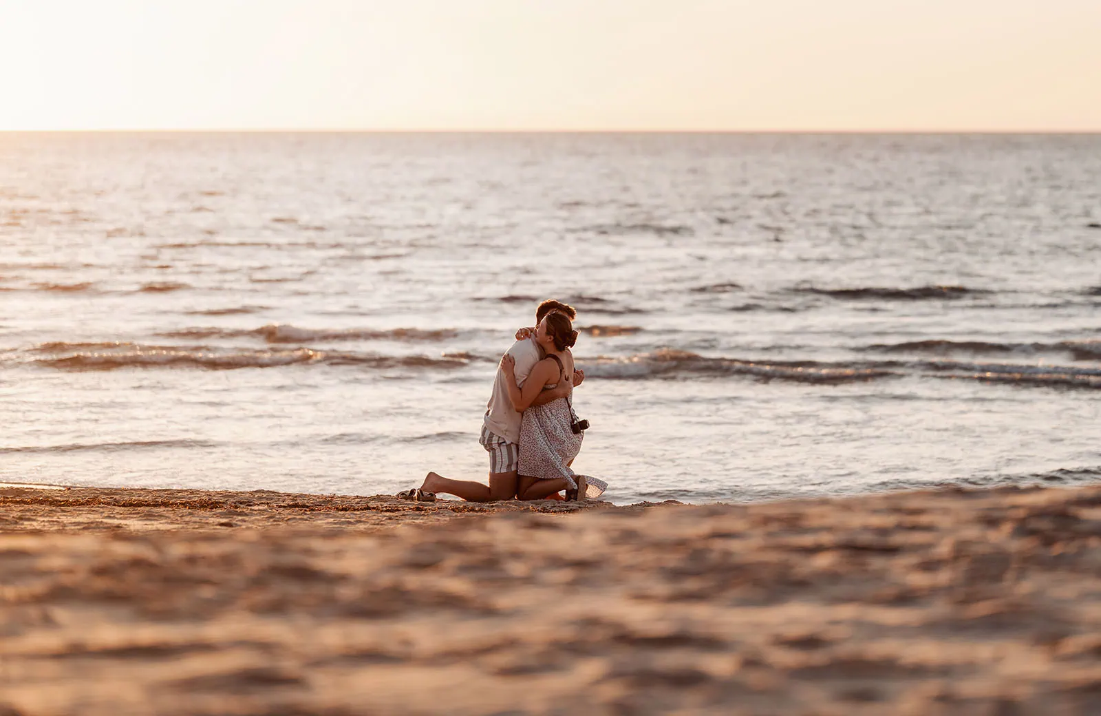 christies beach proposal – hollie & william 34 Romantic beach sunset embrace; couple, ocean, camera, tranquility, golden hour reflection.
