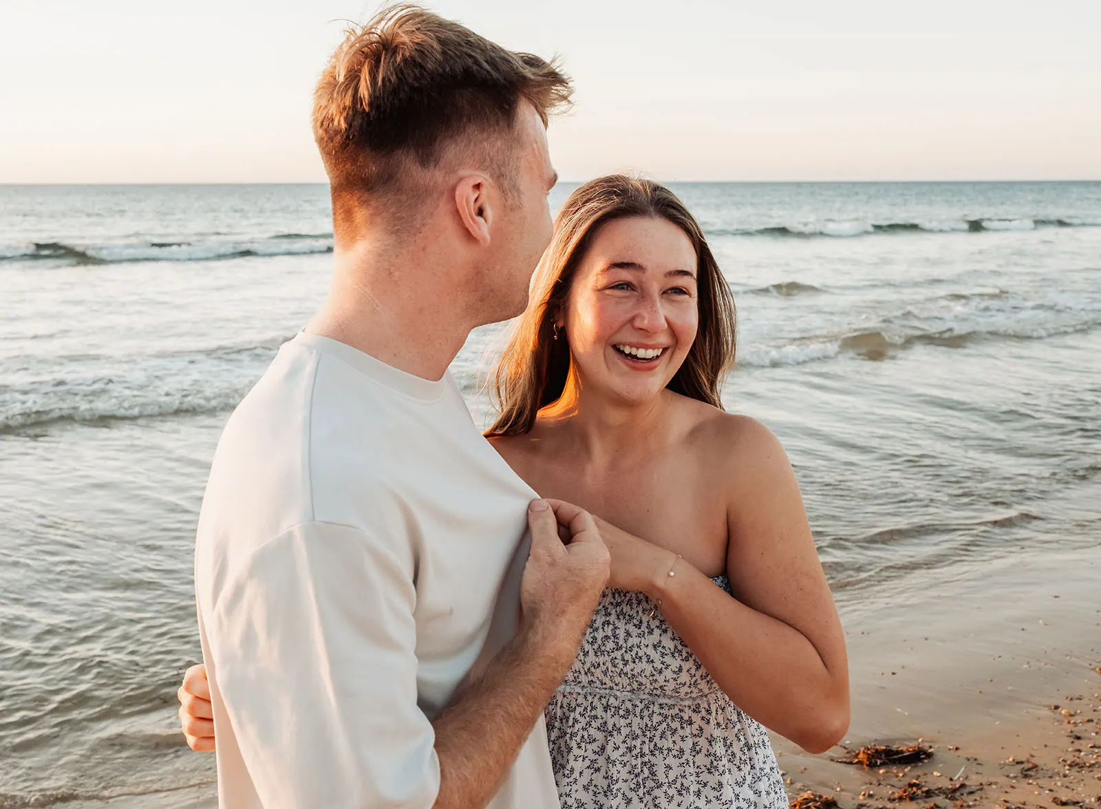 christies beach proposal – hollie & william 40 Couple embracing on a sunny beach, ocean waves, serene sunset, joyful expressions, natural beauty.