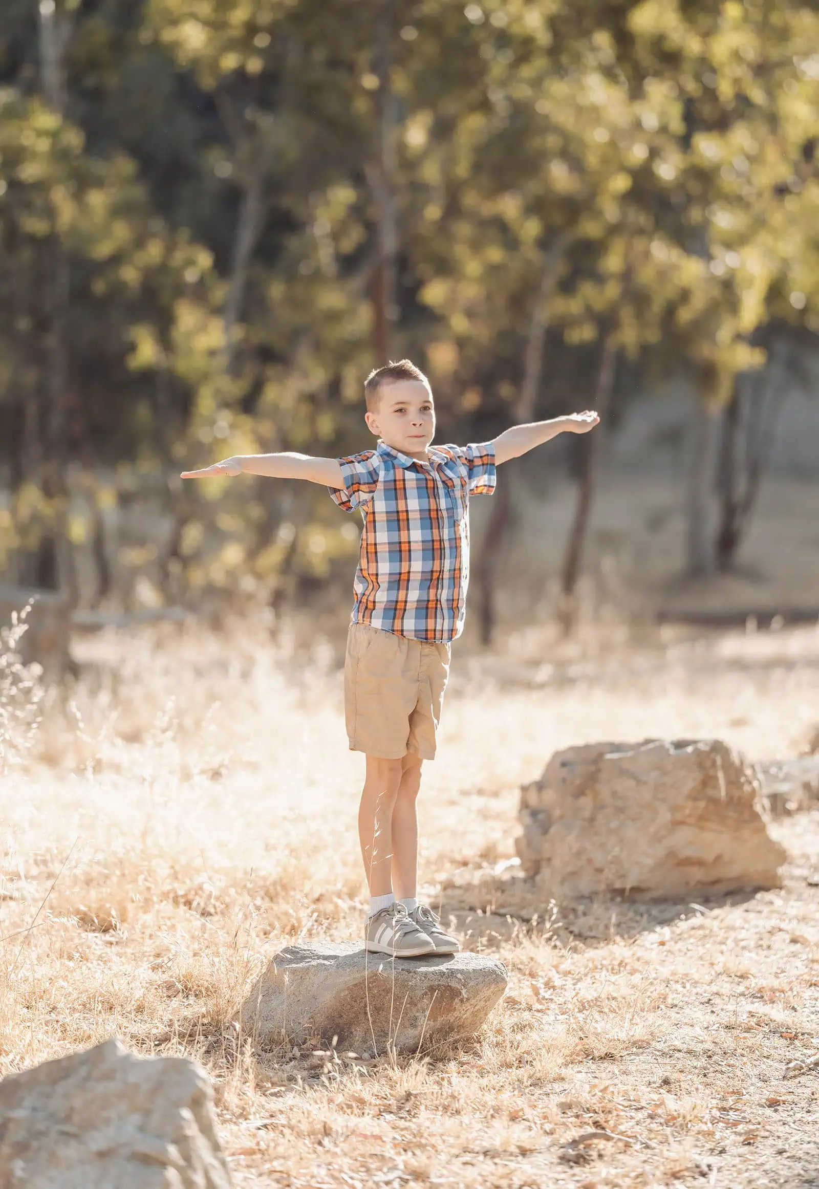 beautiful anstey hill family photoshoot 17 Boy balancing on a rock in nature, wearing colorful clothes and enjoying outdoor adventure.